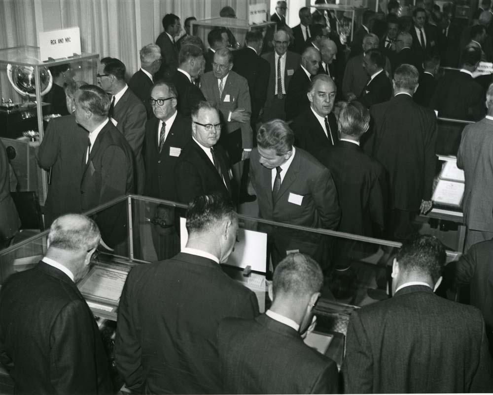 The crowded opening of the Sarnoff library, many guests inspect cases of artifacts