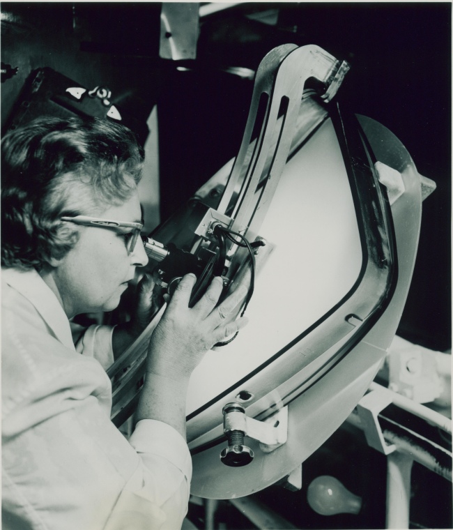 A woman uses a microscope to inspect a tube