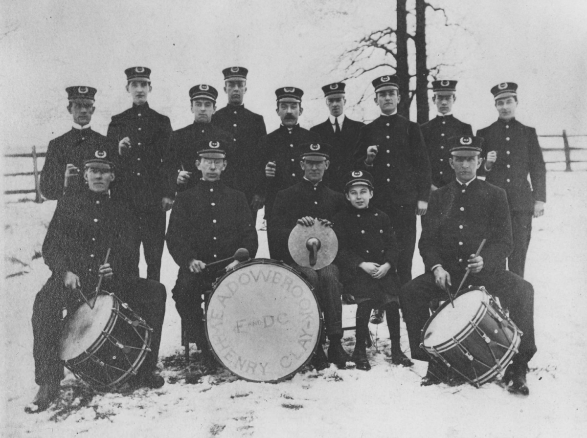 A drum corps poses for a group photo outside in the winter in their band uniforms.