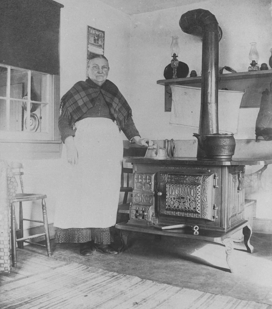 Ellen Maxwell, an older woman, stands at her kitchen stove in the 1800s.