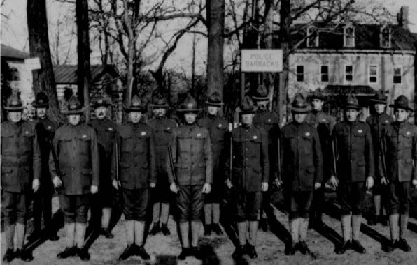 military police in uniform stand in formation in front of their barracks