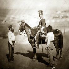 Soldier on his horse, two helpers stand nearby