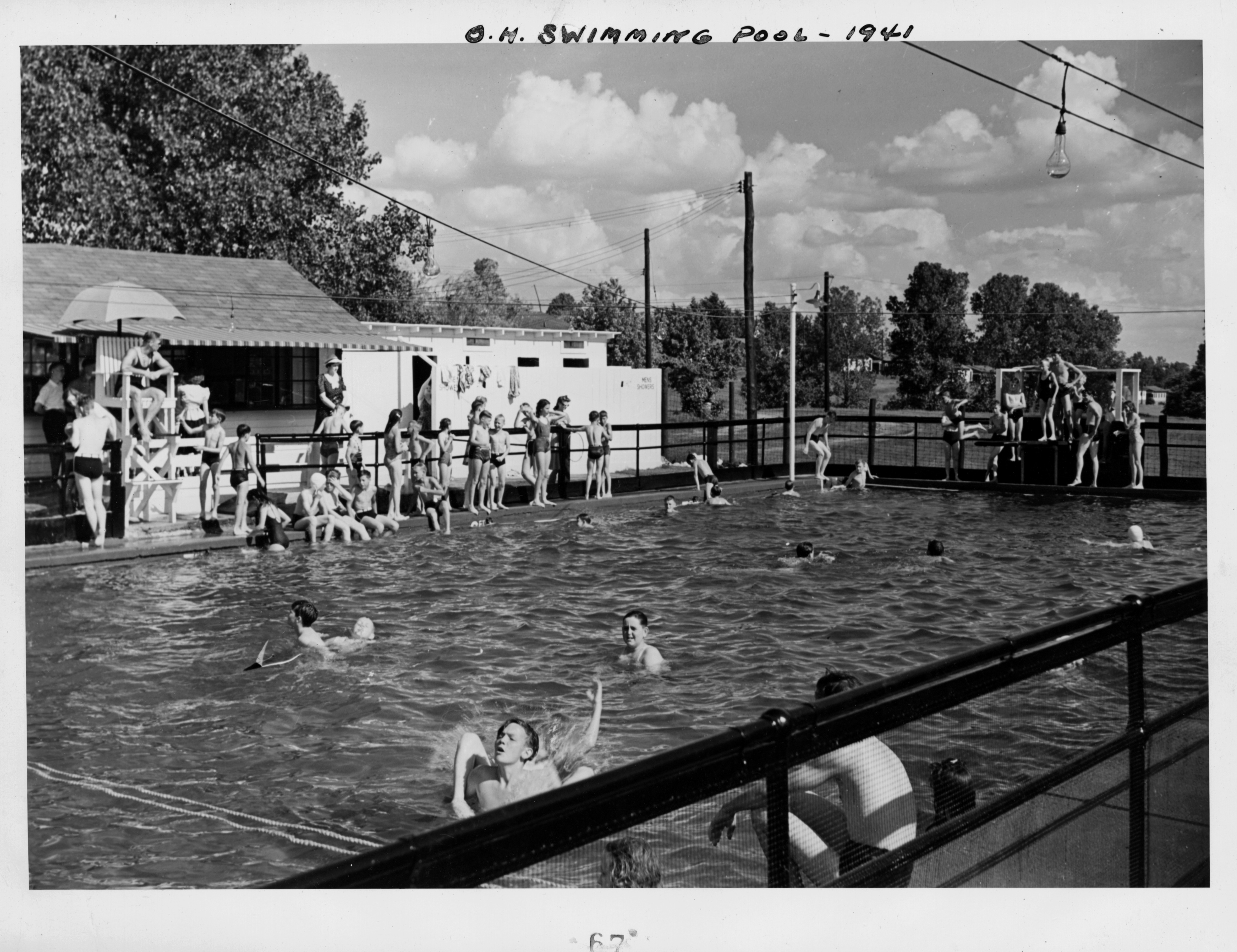 Black and white photograph of a pool full of young people.