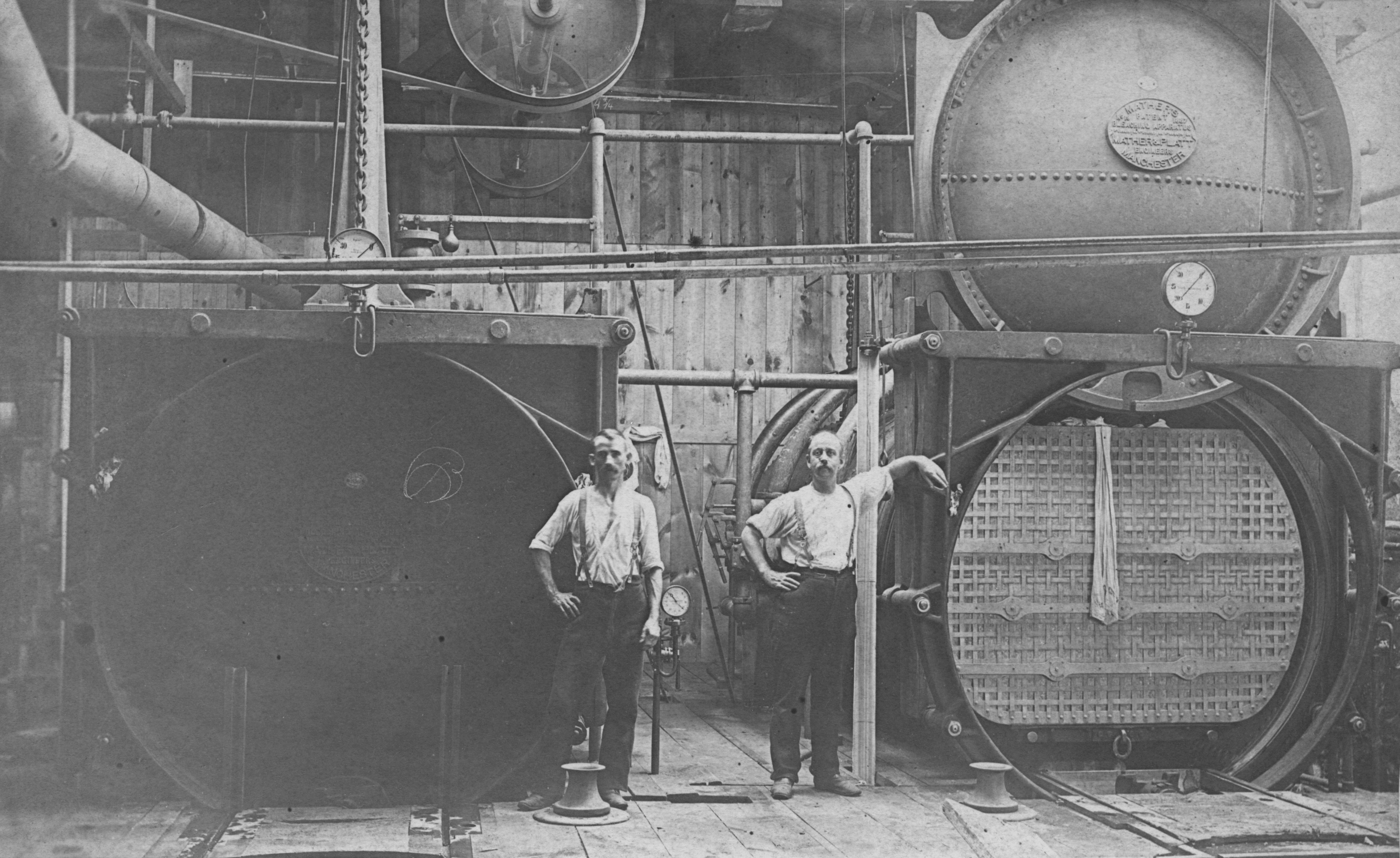 Black and white image of two workers with bleaching machines at Joseph Bancroft & Sons Co. mill