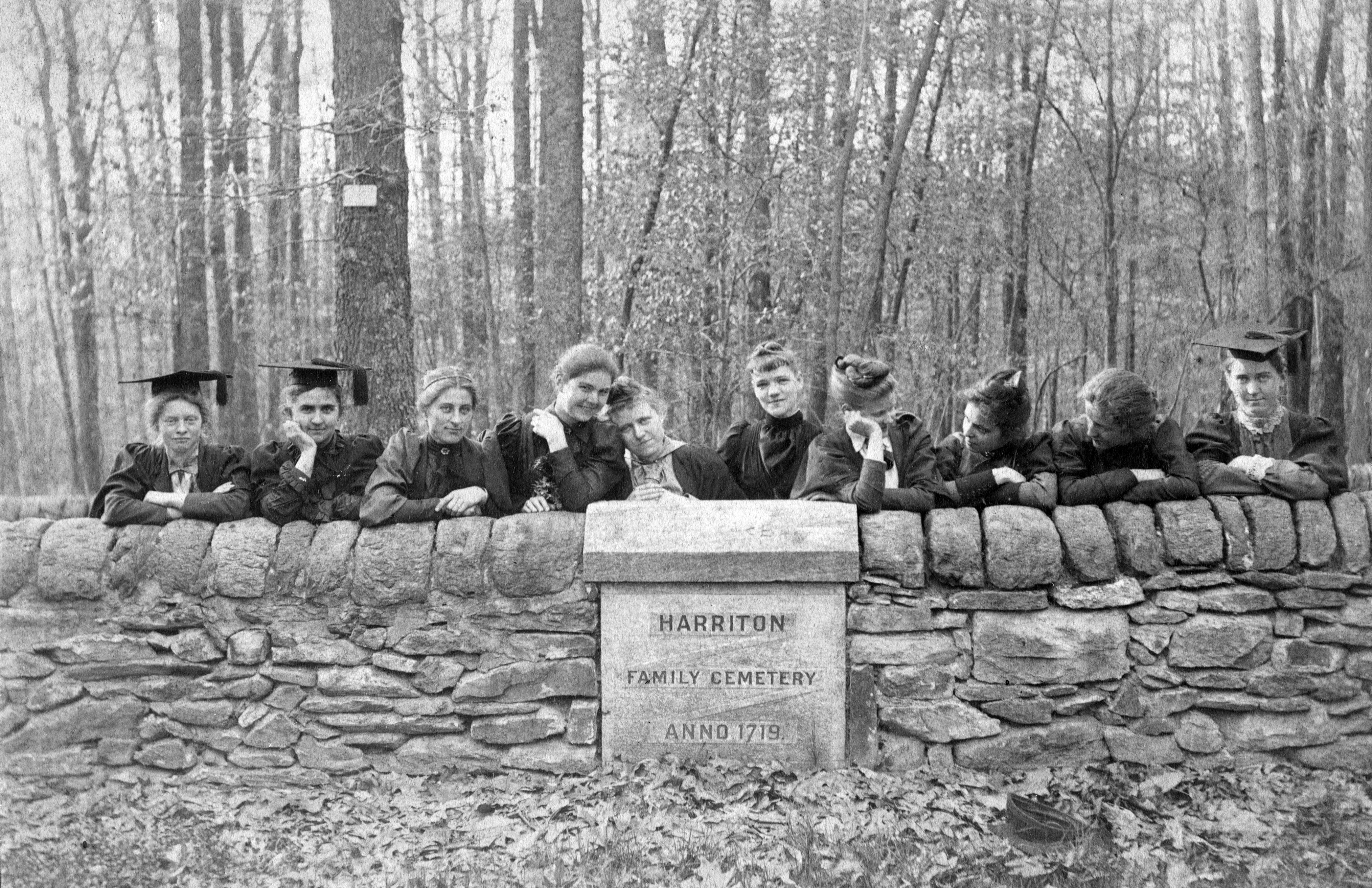 Black and white photo of women posing behind a low wall for a family cemetery plot.