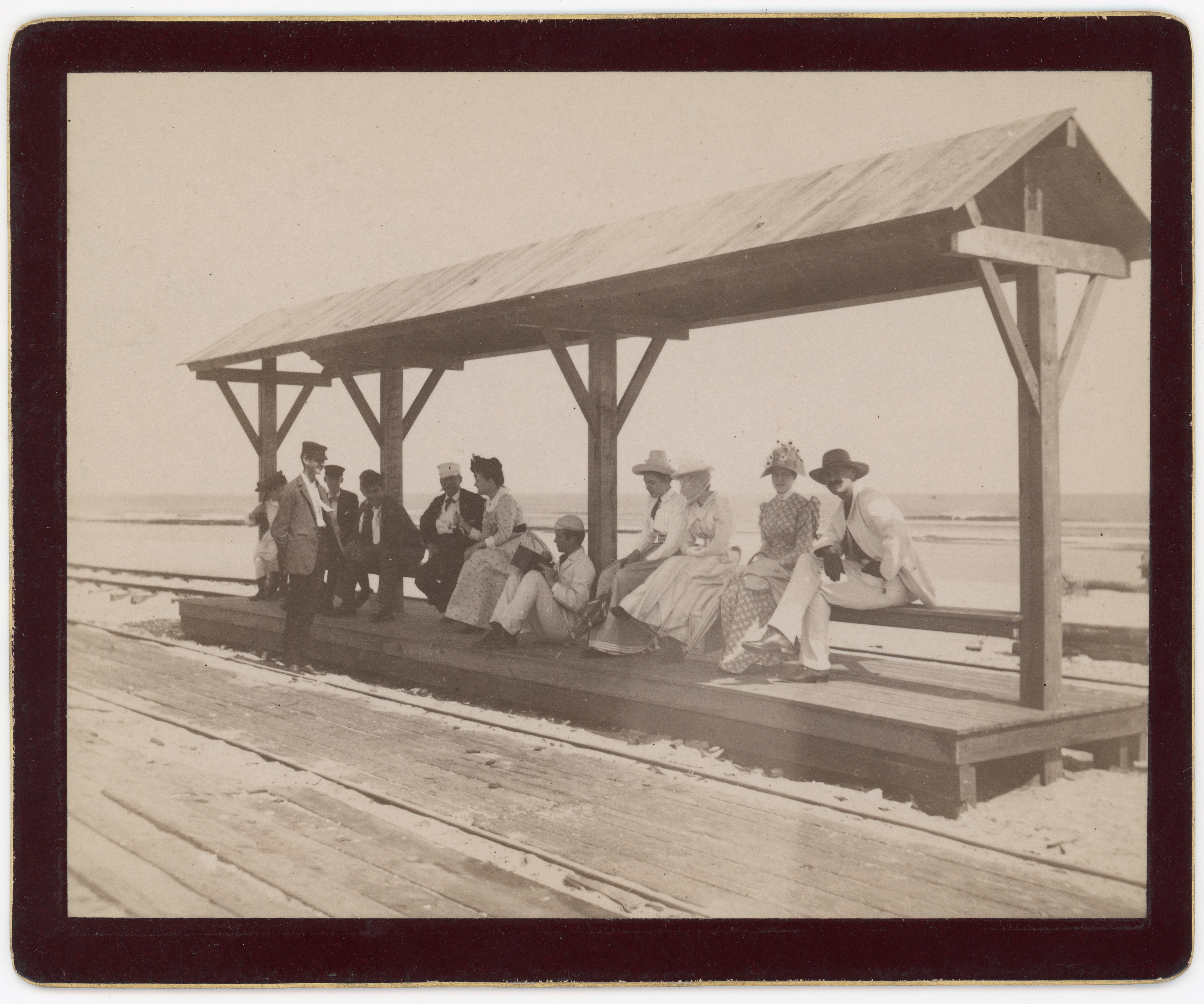 Black and white photograph of a group of people assembled at a seaside streetcar station.