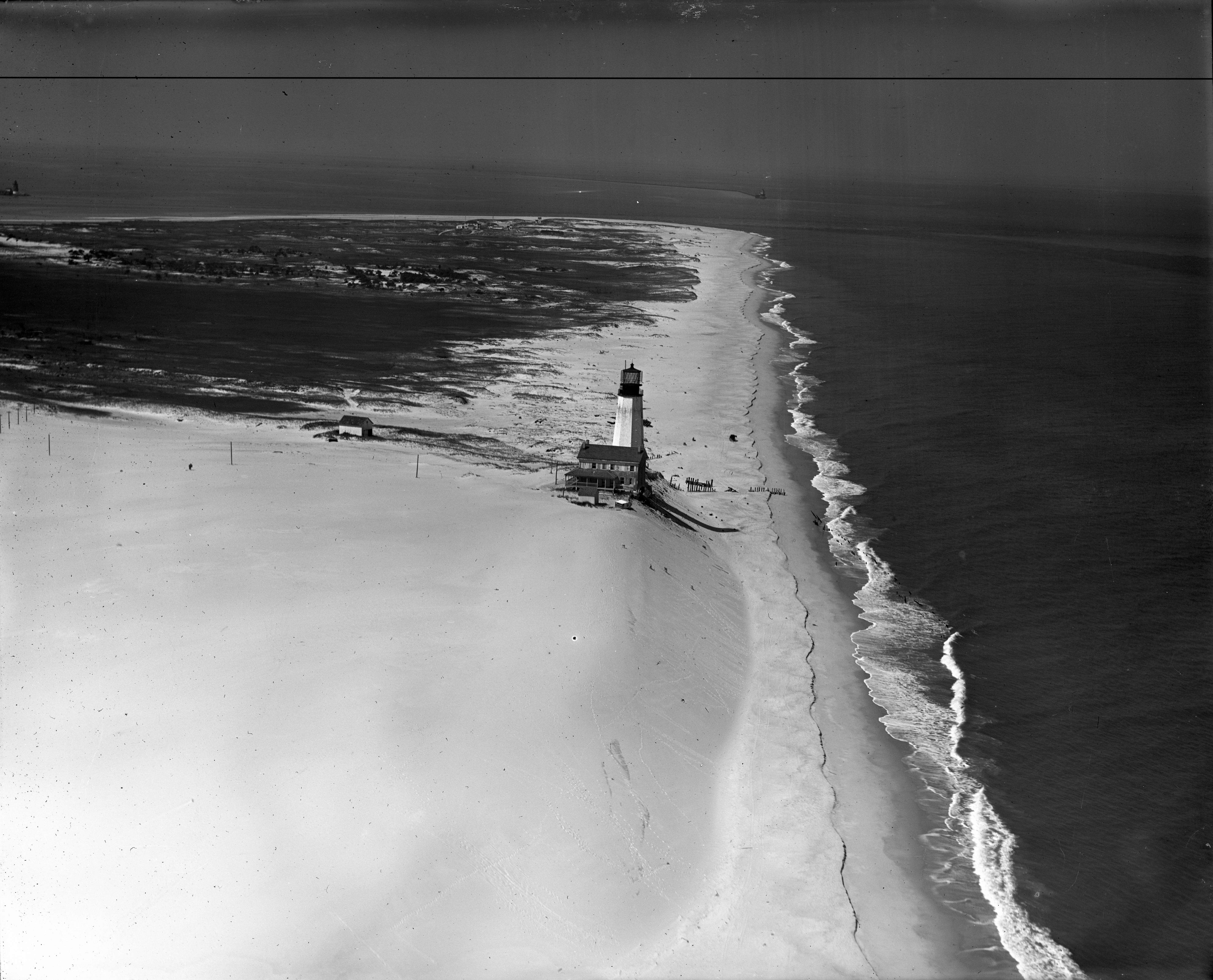 Black and white aerial photograph of the Cape Henlopen Lighthouse and surrounding landscape.