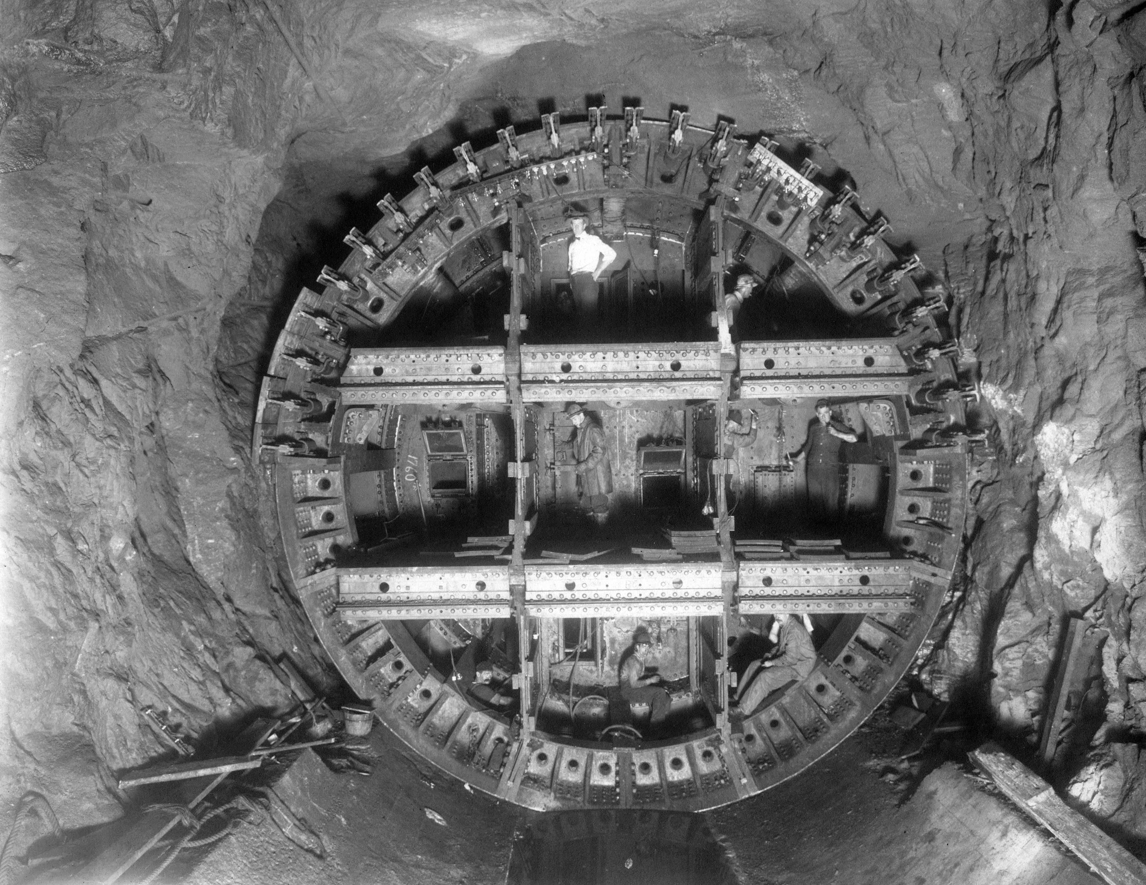 Black and white photograph of workers building a large underground tunnel.