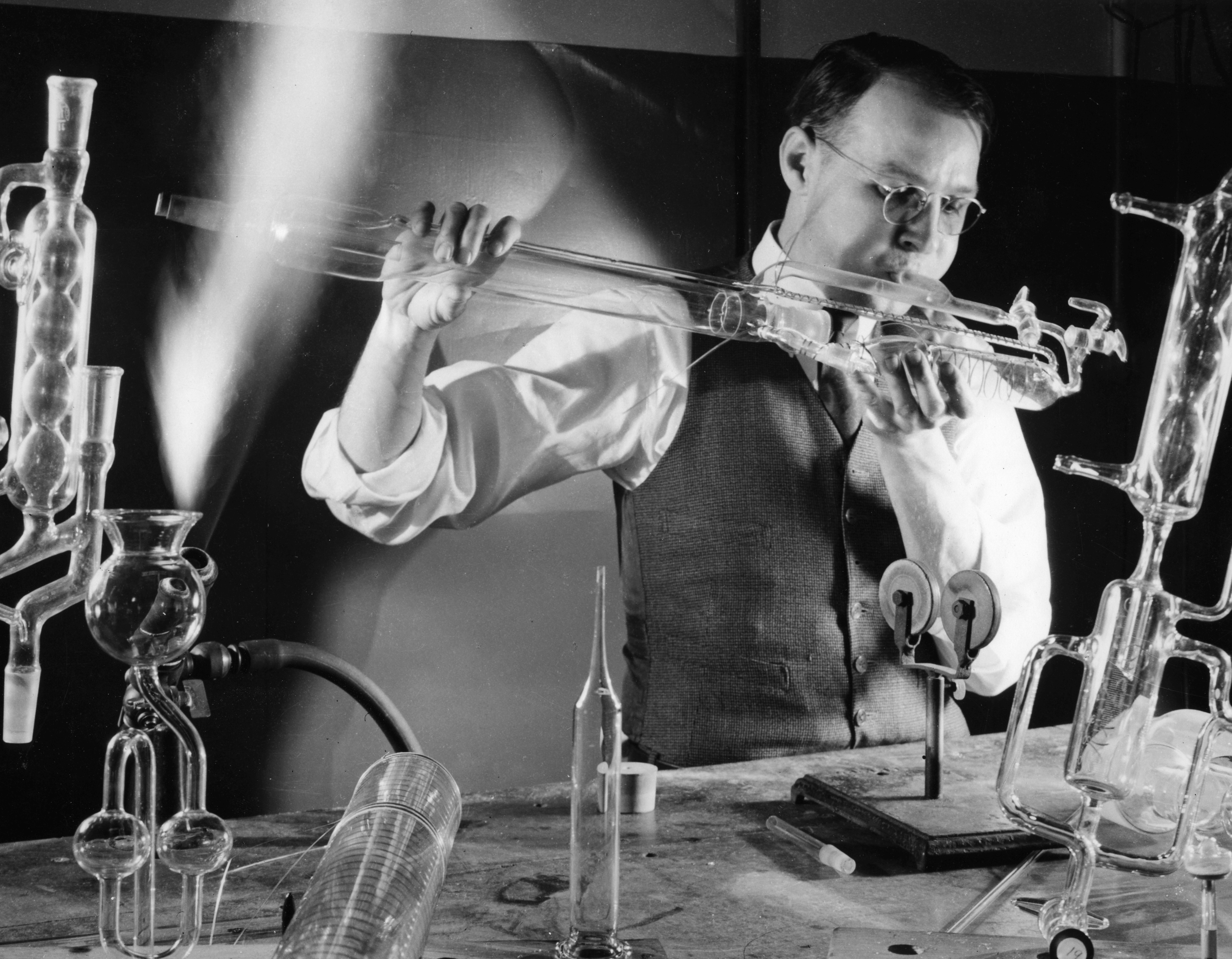 Black and white image of a glass blower making chemical laboratory glassware