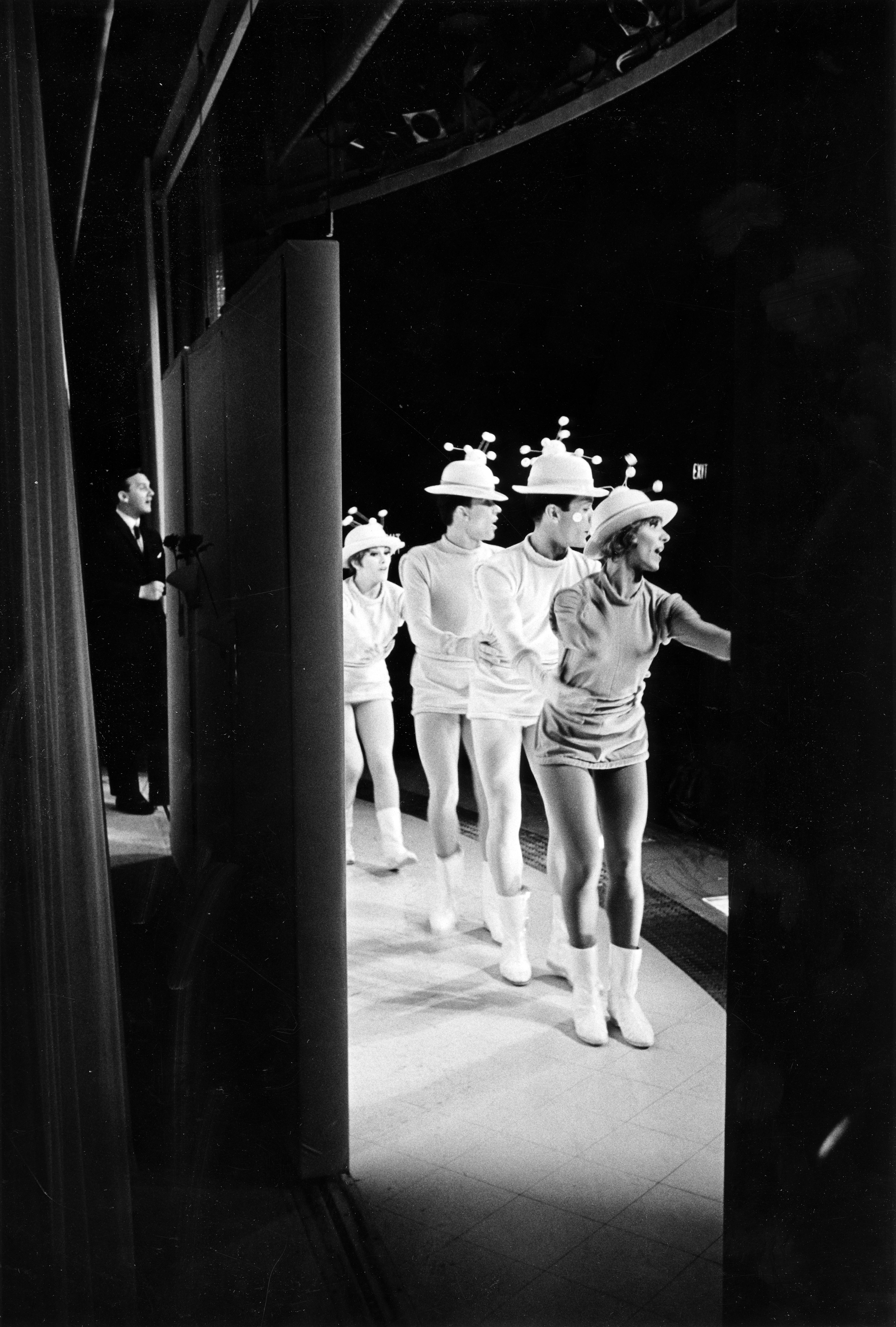 Black and white image of dancers dressed as moleculues performing on a stage.