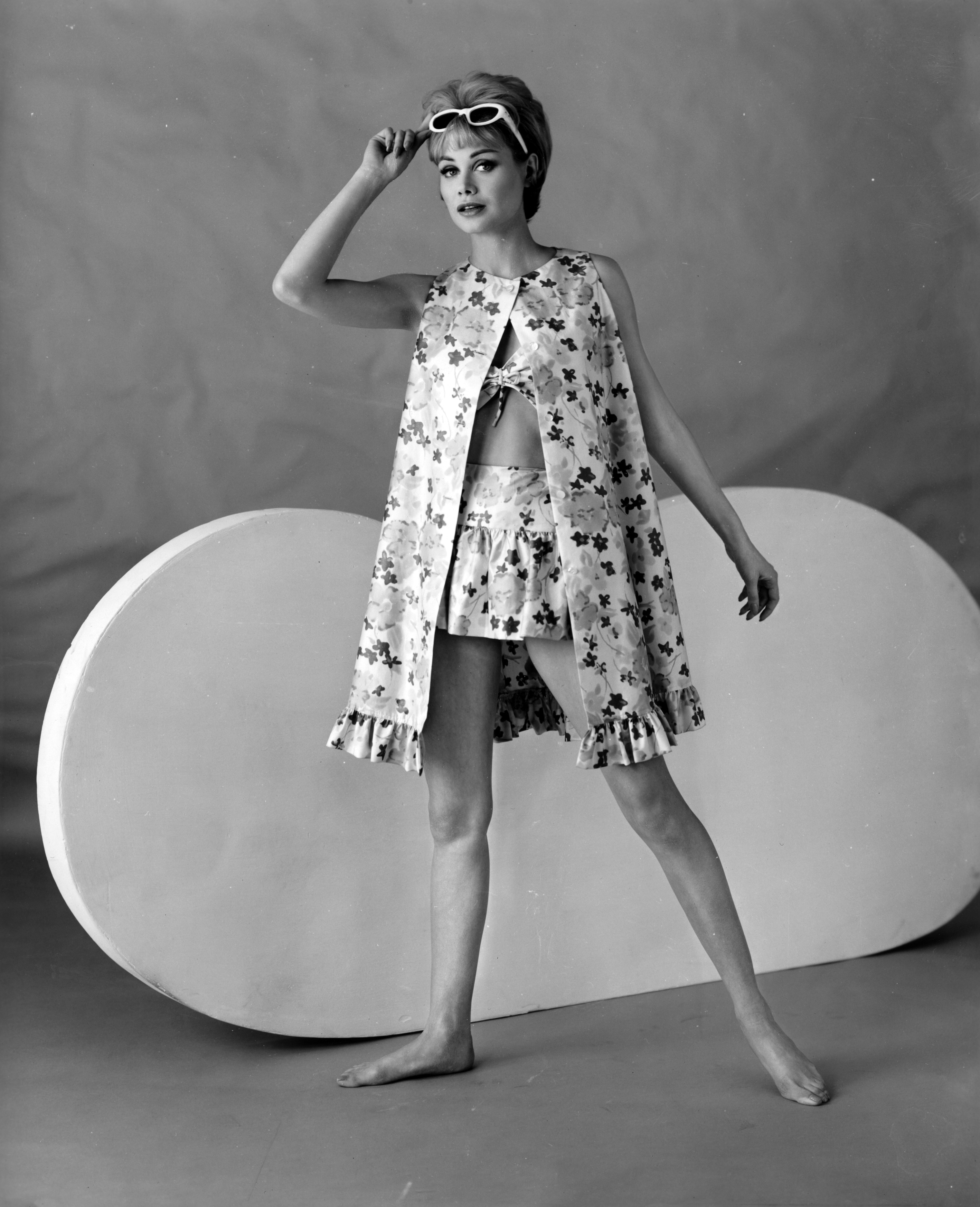 Black and white fashion photo of a woman in a 2-piece bathing suit and cover-up.
