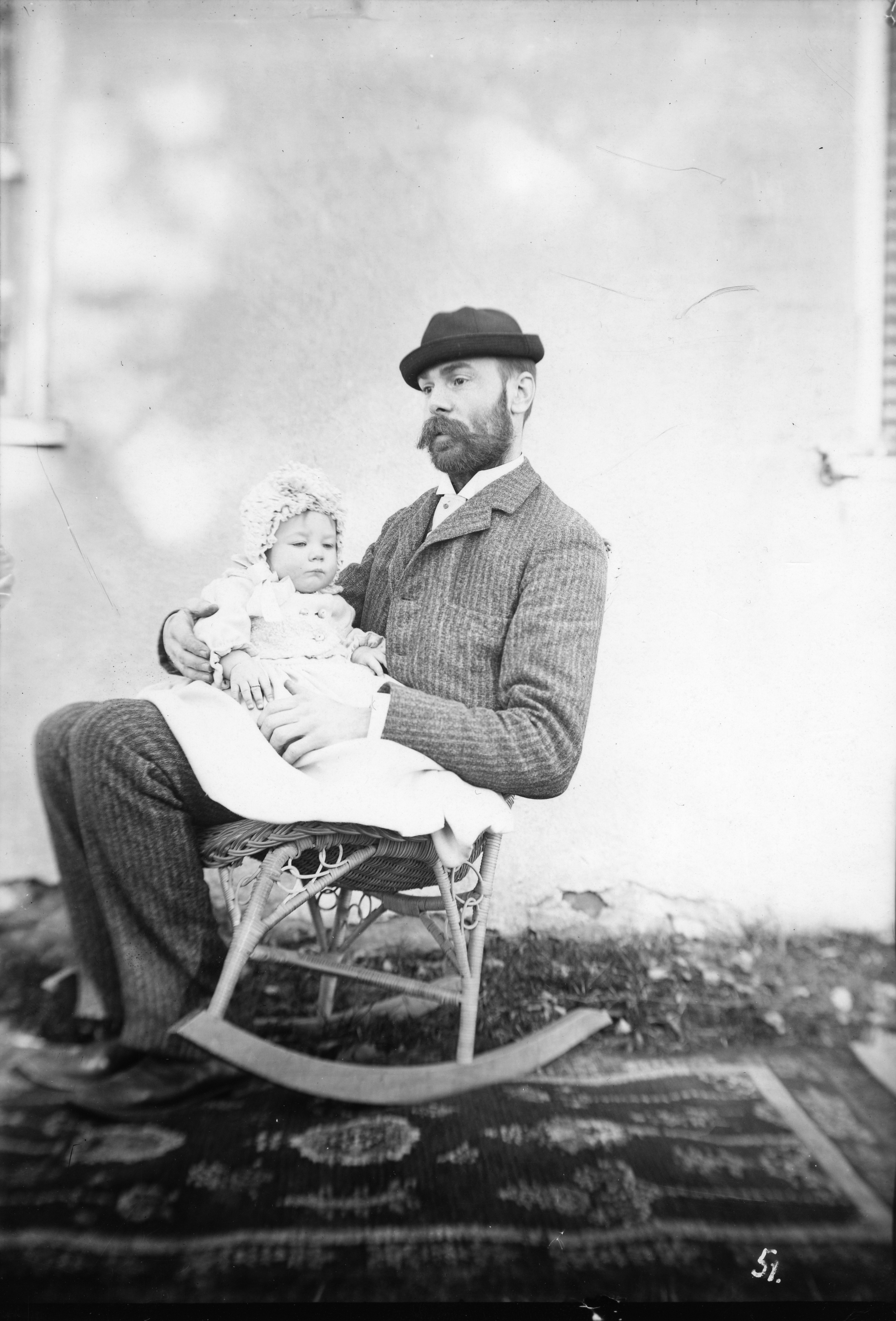 Black and white image of a man in a rocking chair with an infant in his lap