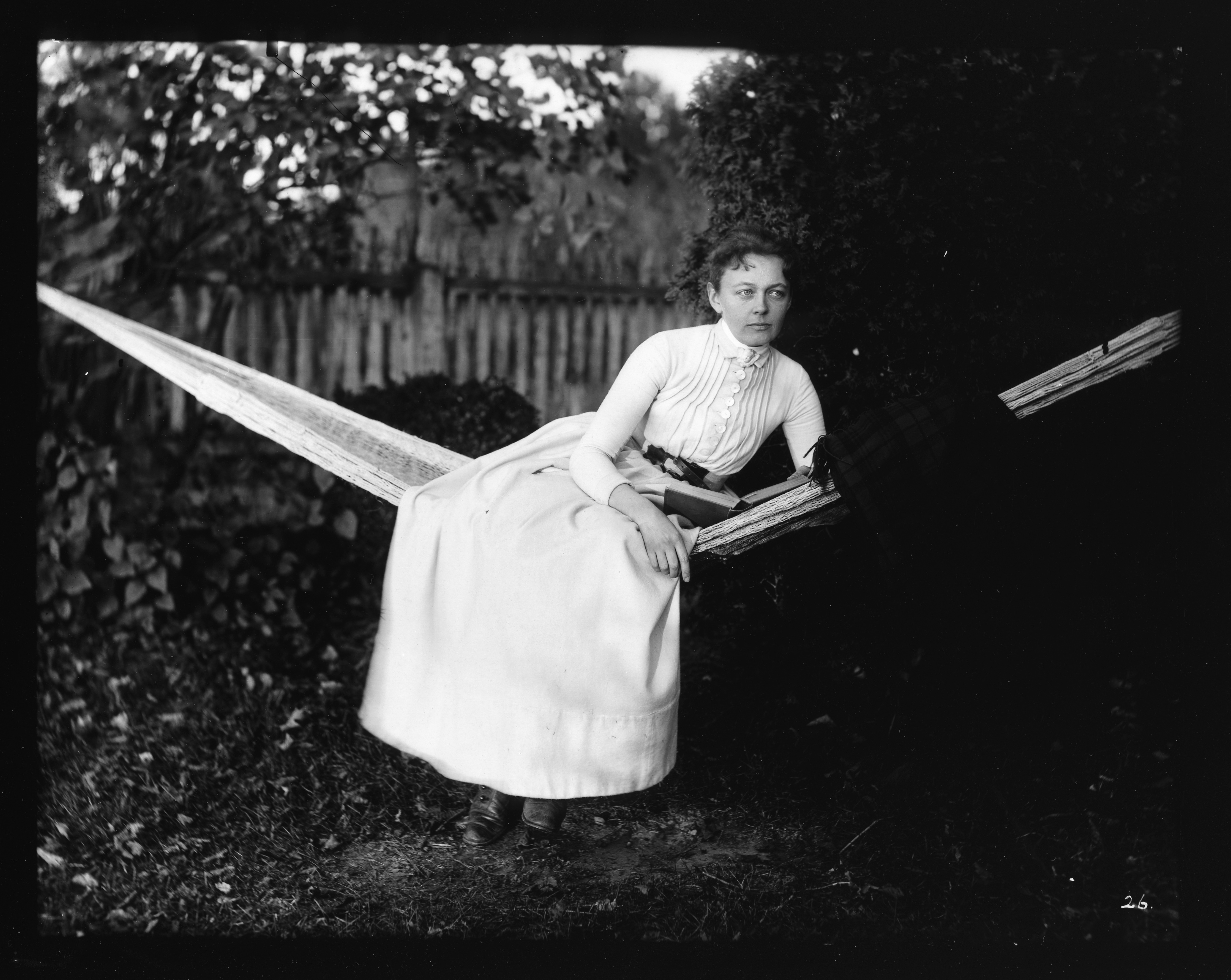 Black and white image of a woman in a hammock with a book.