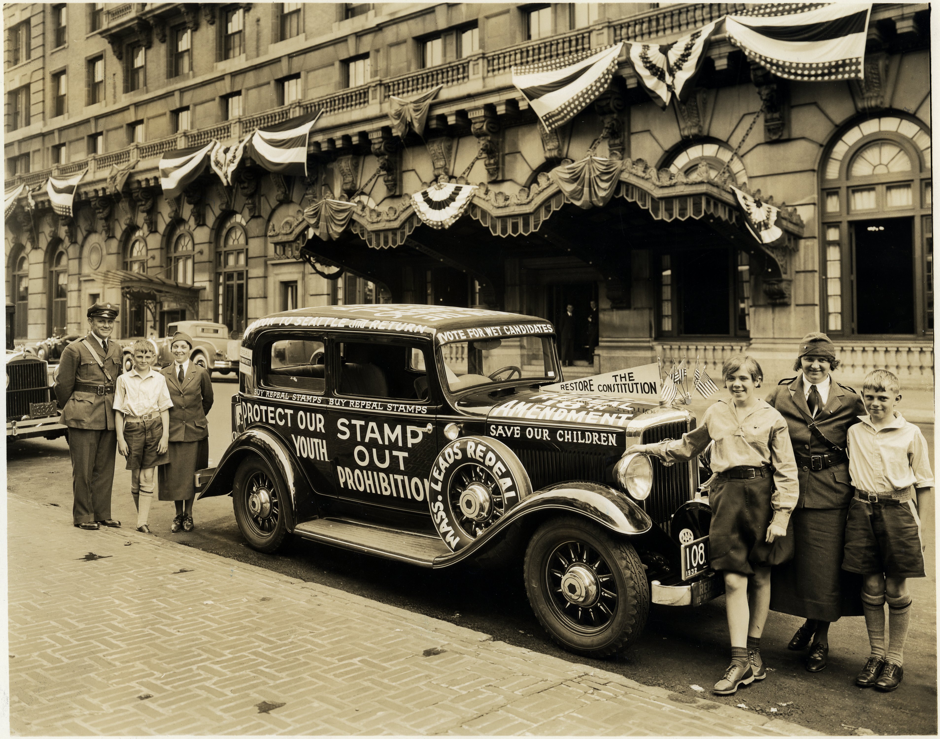 Children and police officers posing with car decorated with anti-Prohibition slogans.
