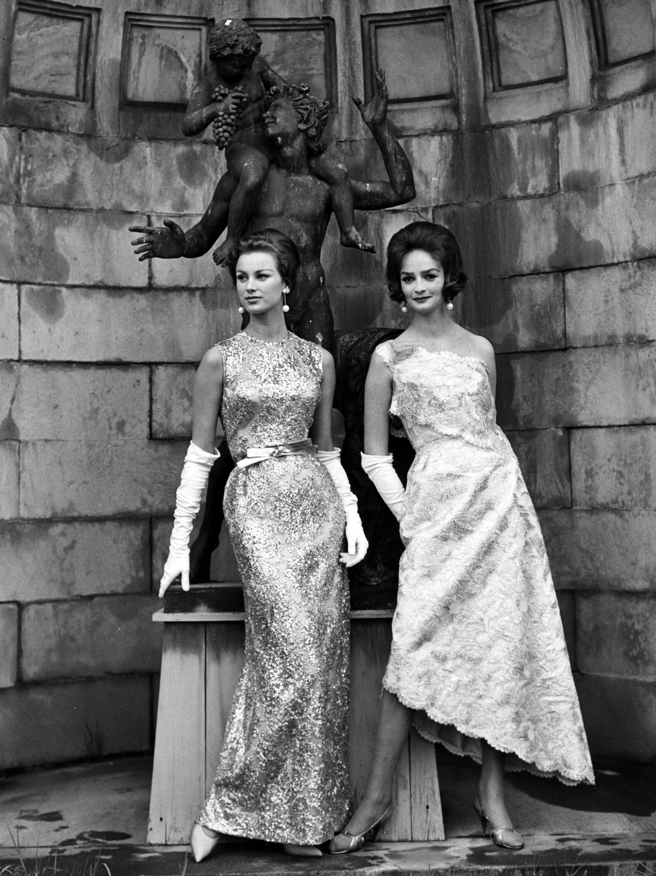 Black and white fashion photograph of two women in glittery evening gowns.