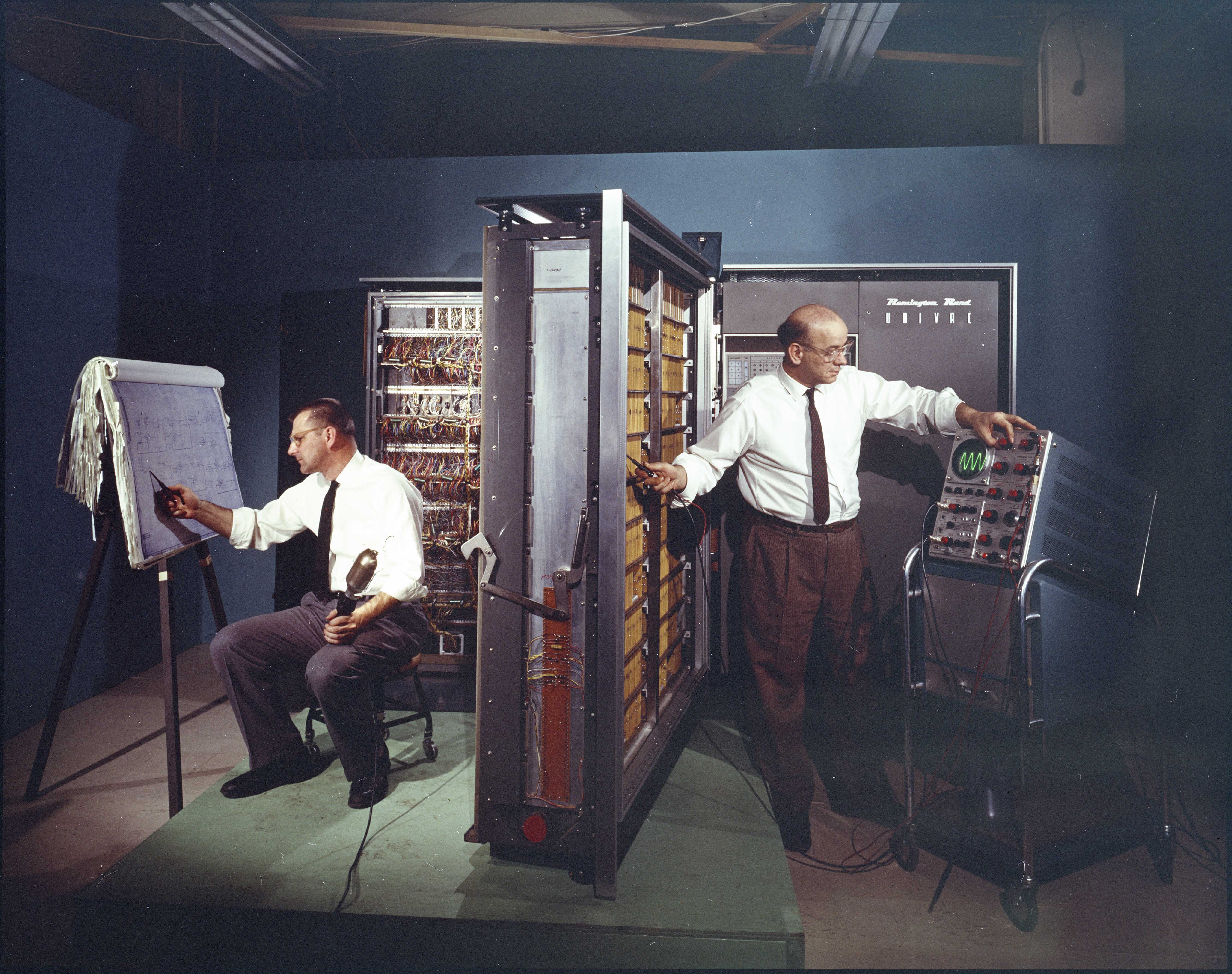 Color image of two men installing a large UNIVAC computer