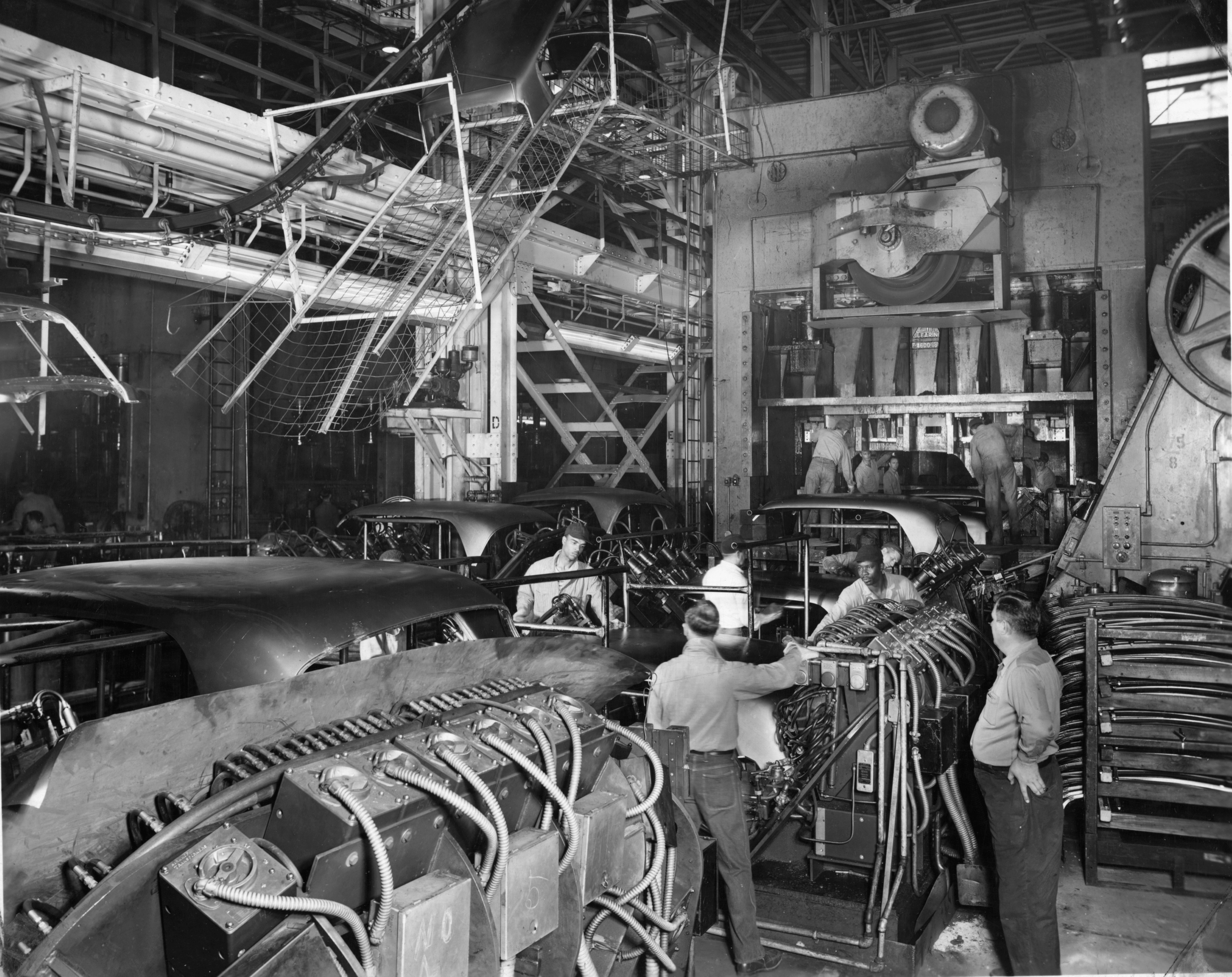 Black and white image of workers assembling automobiles