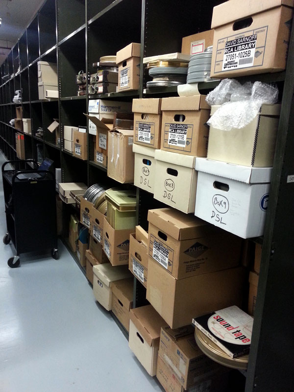 Library shelves holding some of the Sarnoff materials from boxes to film canisters