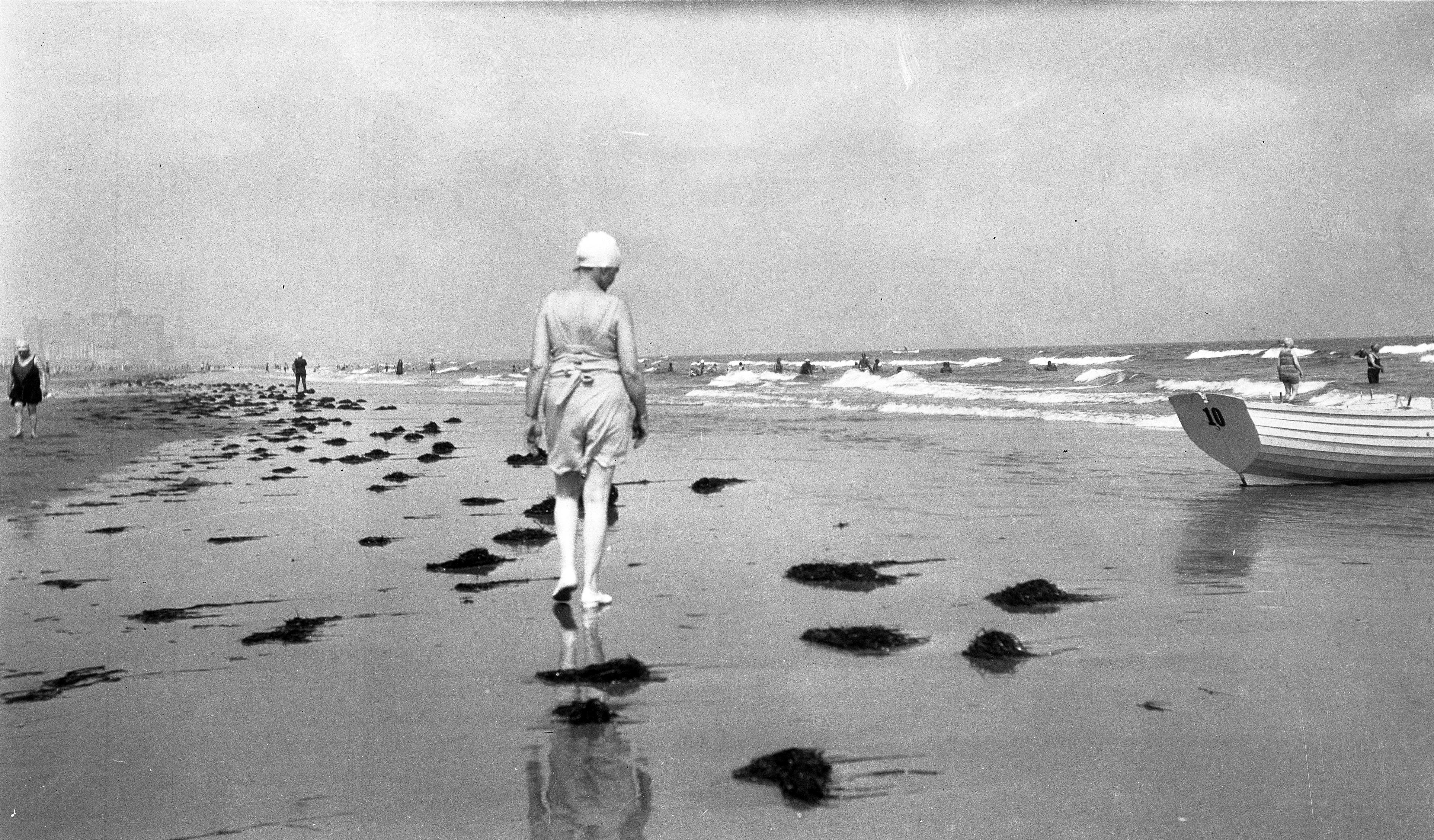 Black and white image of a woman walking on beach with back to camera at Ventnor, New Jersey, or Rehoboth, Delaware