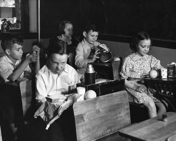 Black and white photograph of children seated at school desks.