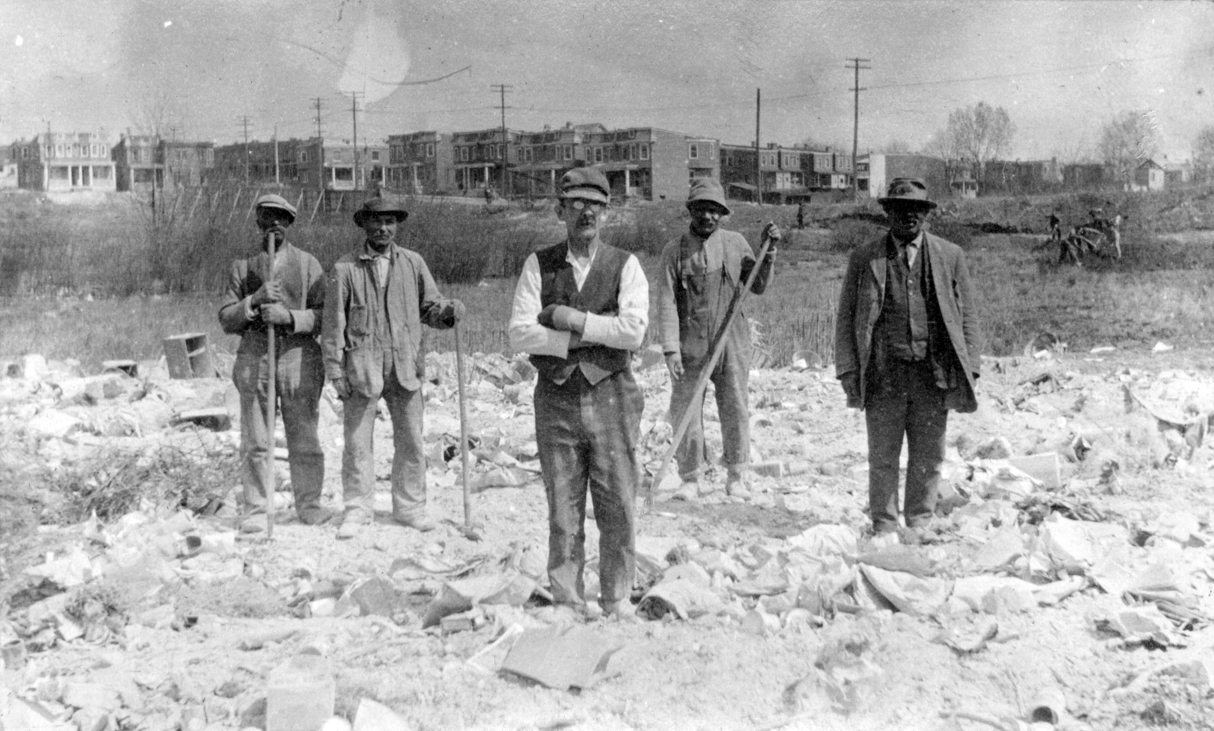 Black and white image of workmen on a cleared construction site.