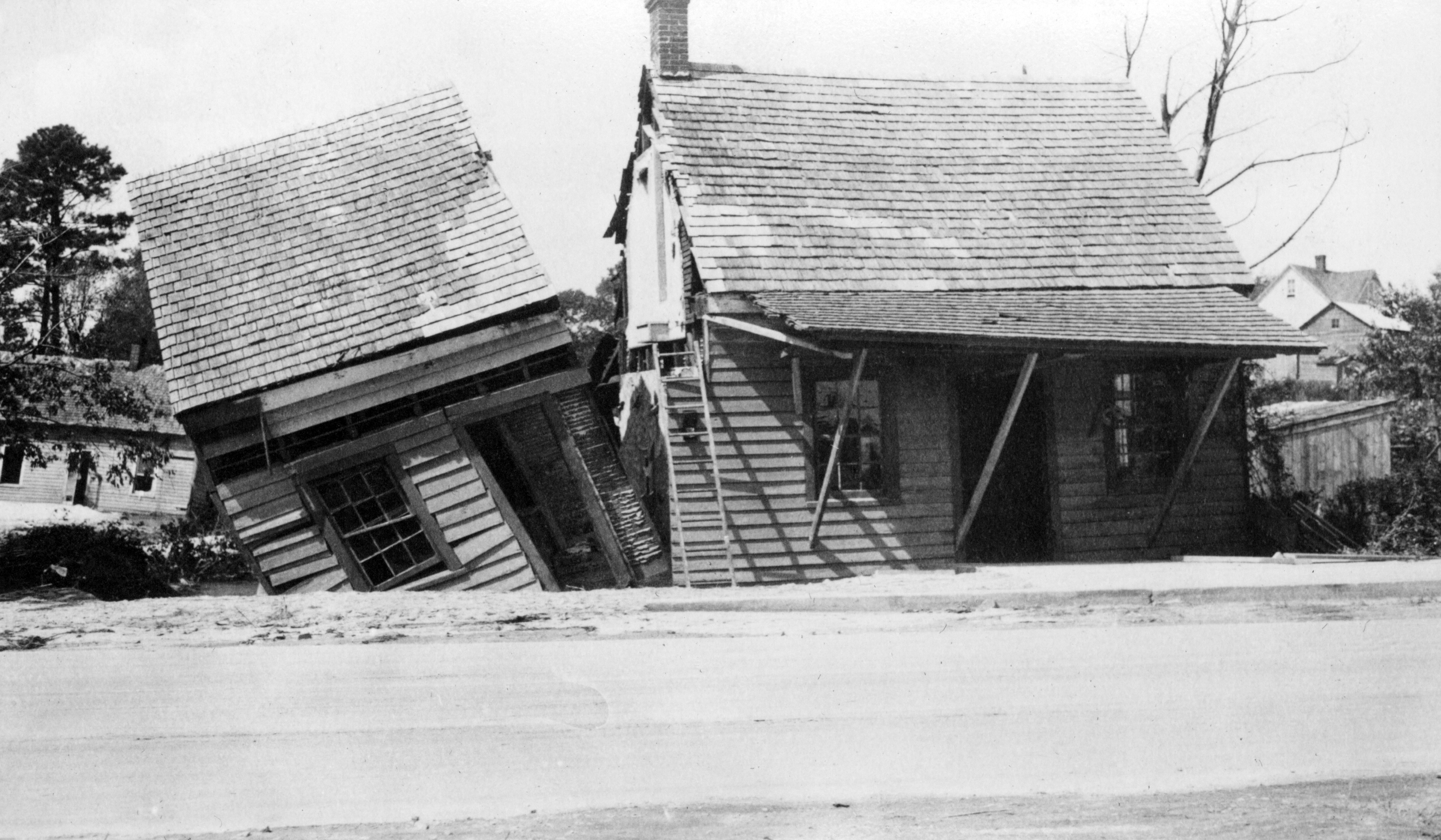 Black and white image of a house split vertically by flooding.