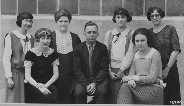 Black and white posed group portrait of six woman and a man in 1920s clothing.