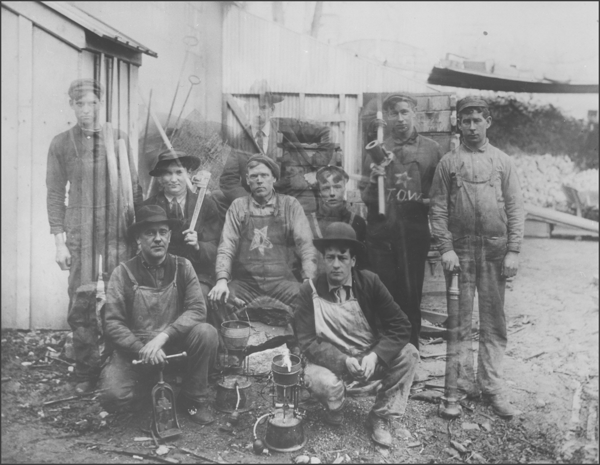 Black and white photograph of a group of workers - some of the men appear transparent as a result of an error in the photographic process.