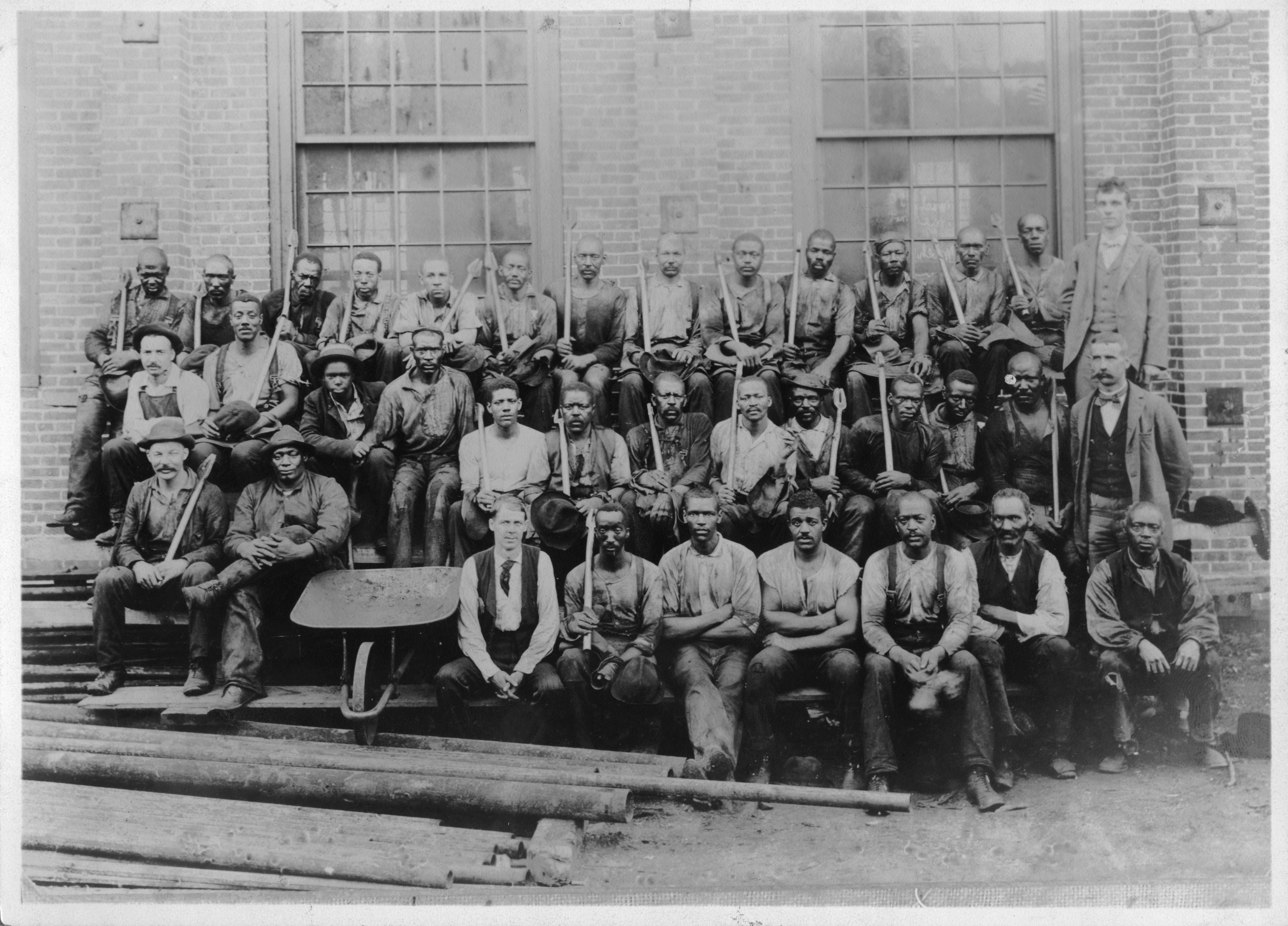 Black and white group photograph of a large number of men in work clothes.