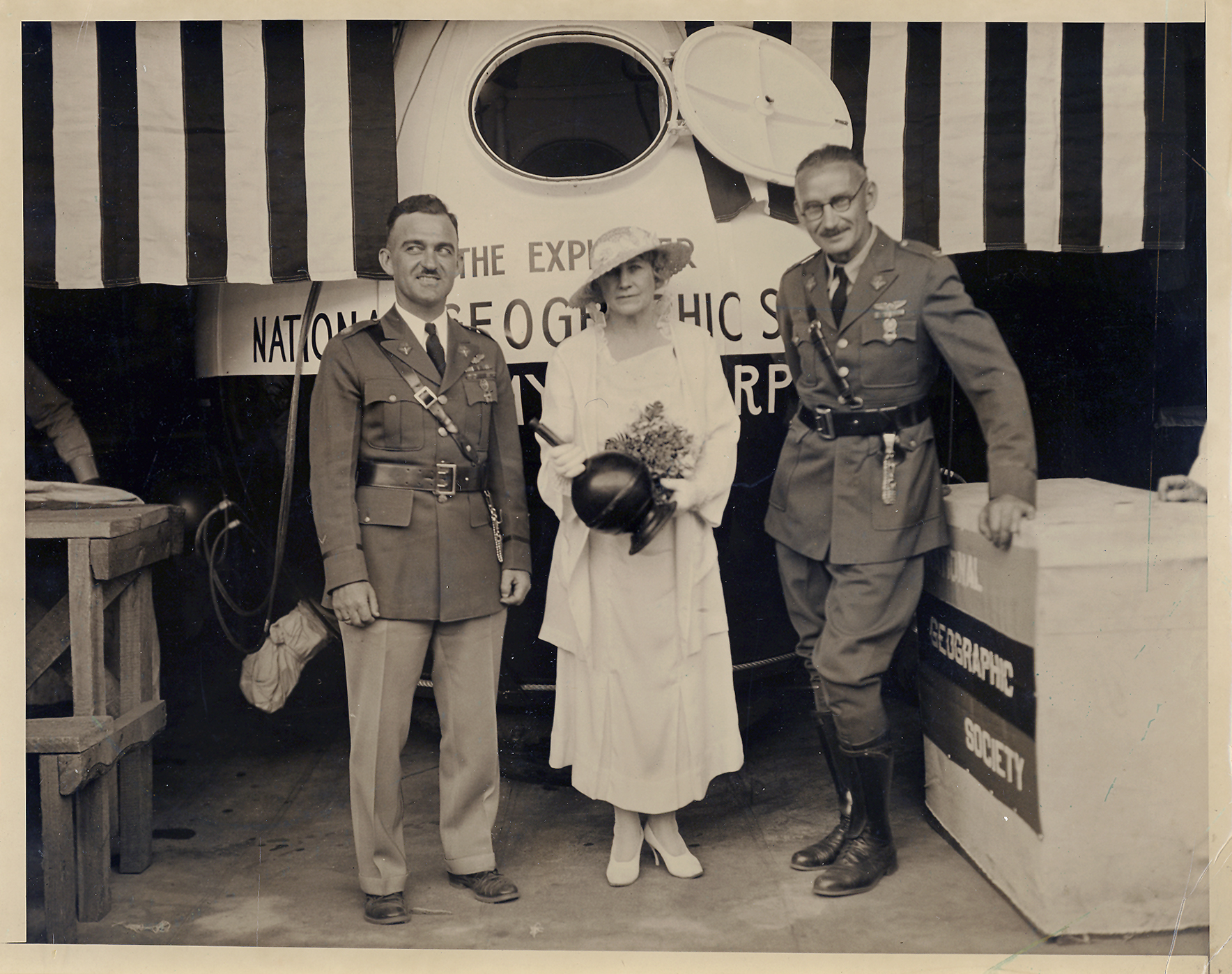 Black and white image of two men and a woman standing in front of a stratosphere gondola balloon.