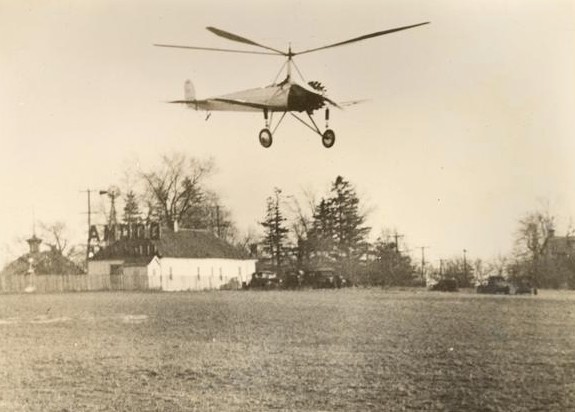 Photograph of an autogiro lifting from the ground at an airfield