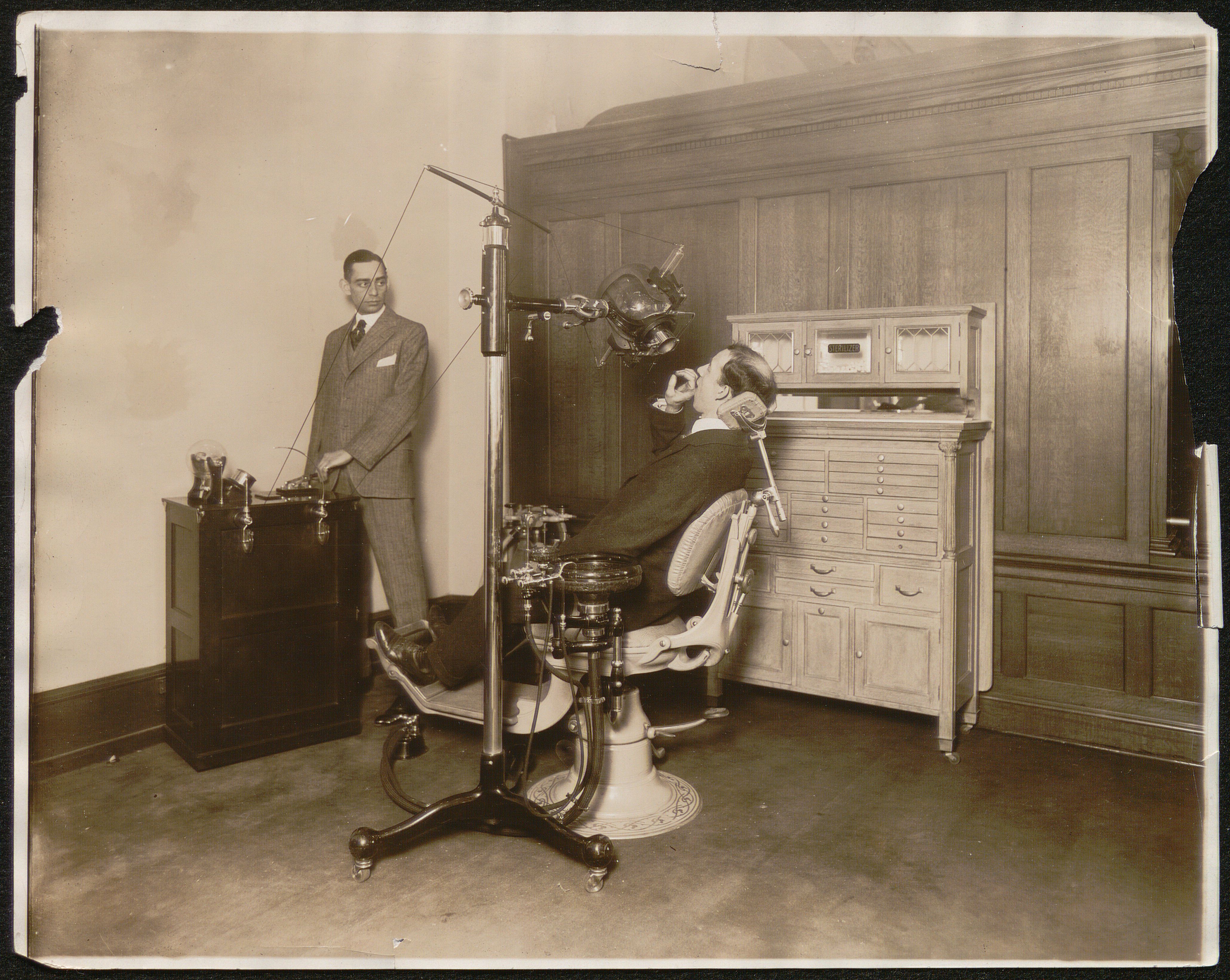 Black and white photograph showing a demonstration of dental x-ray equipment.