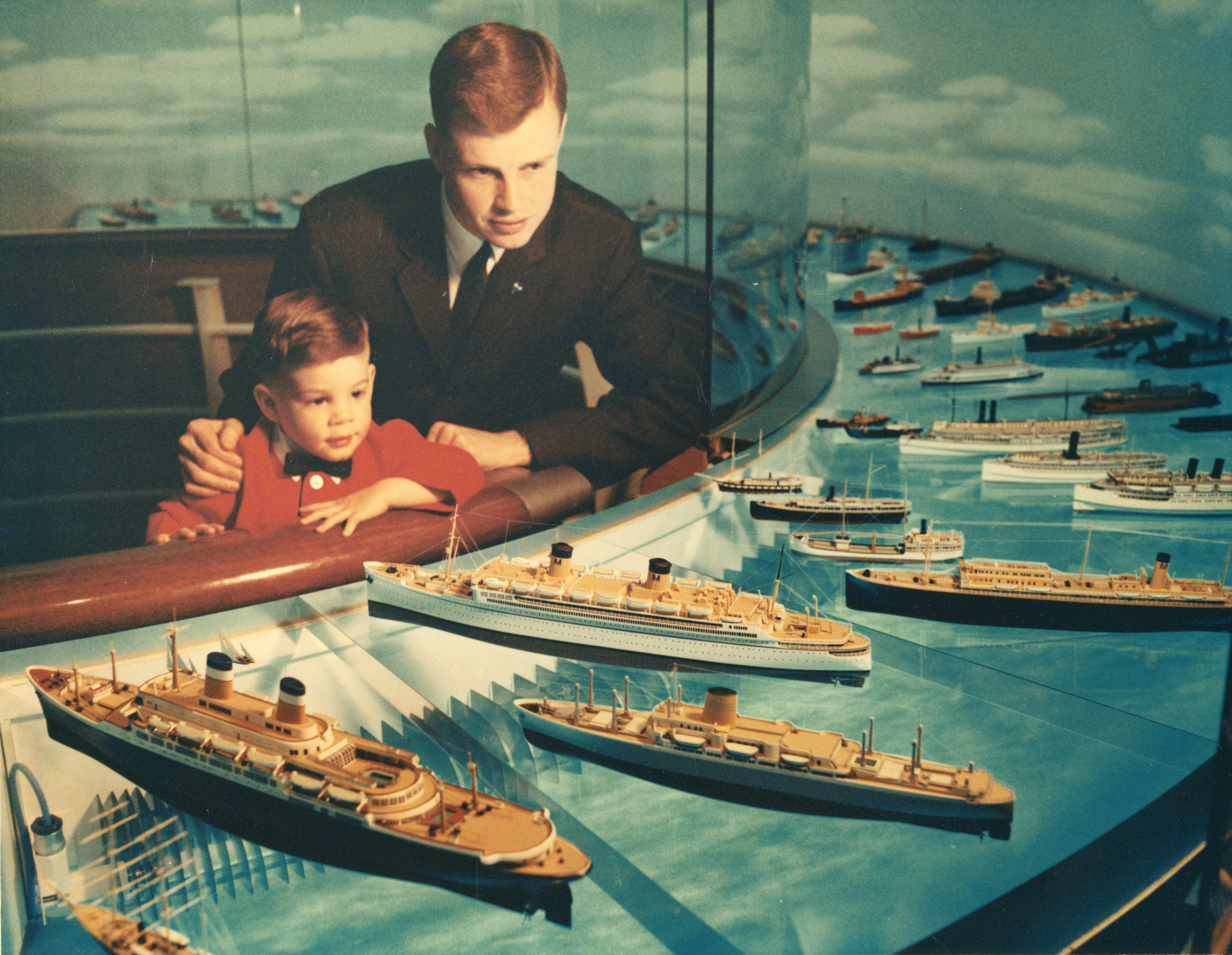 Color photograph of a man and child looking at an exhibit of model ships.