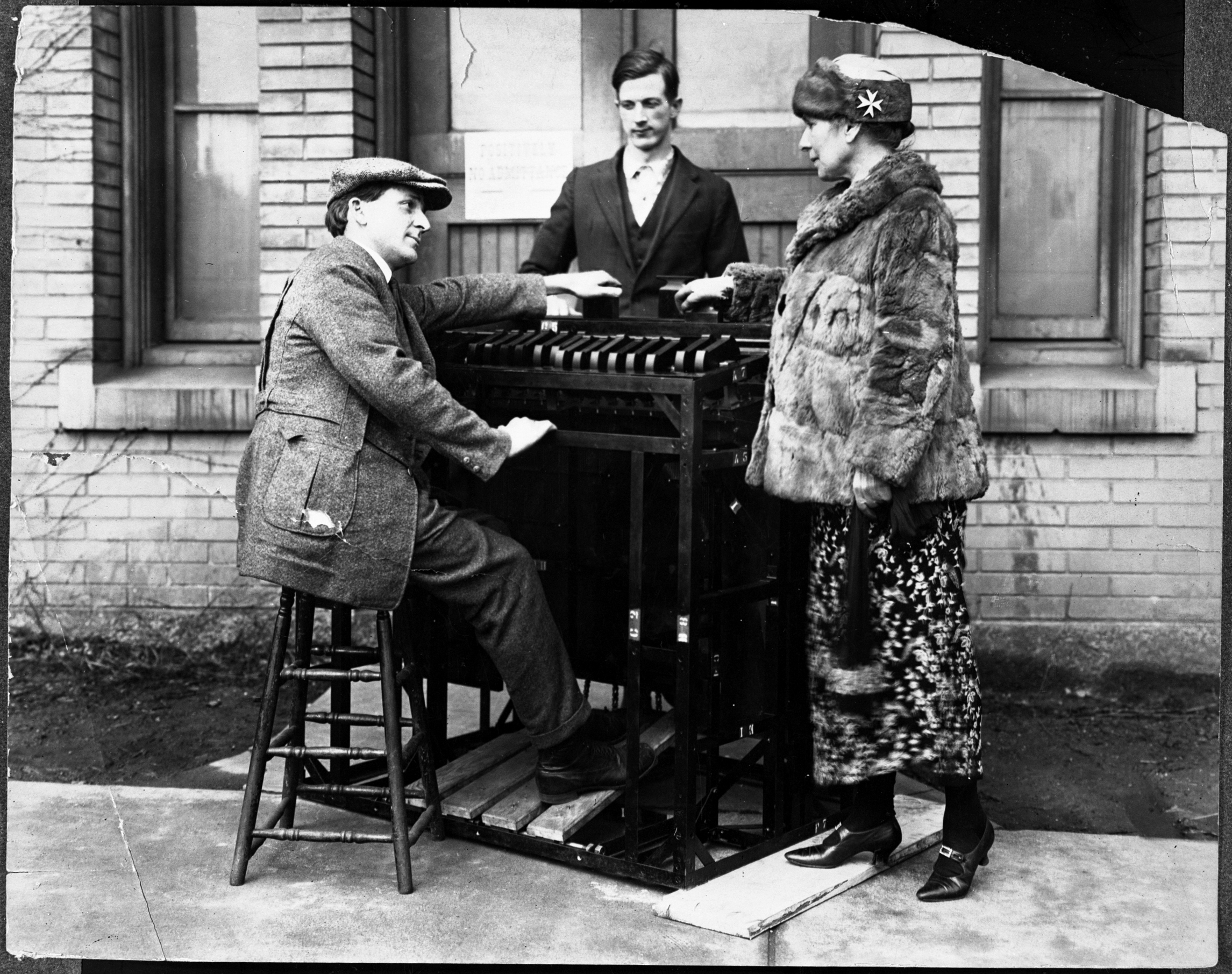 Two men and a woman, arrayed around a 'color organ', which resembles a small, if unusual, piano.