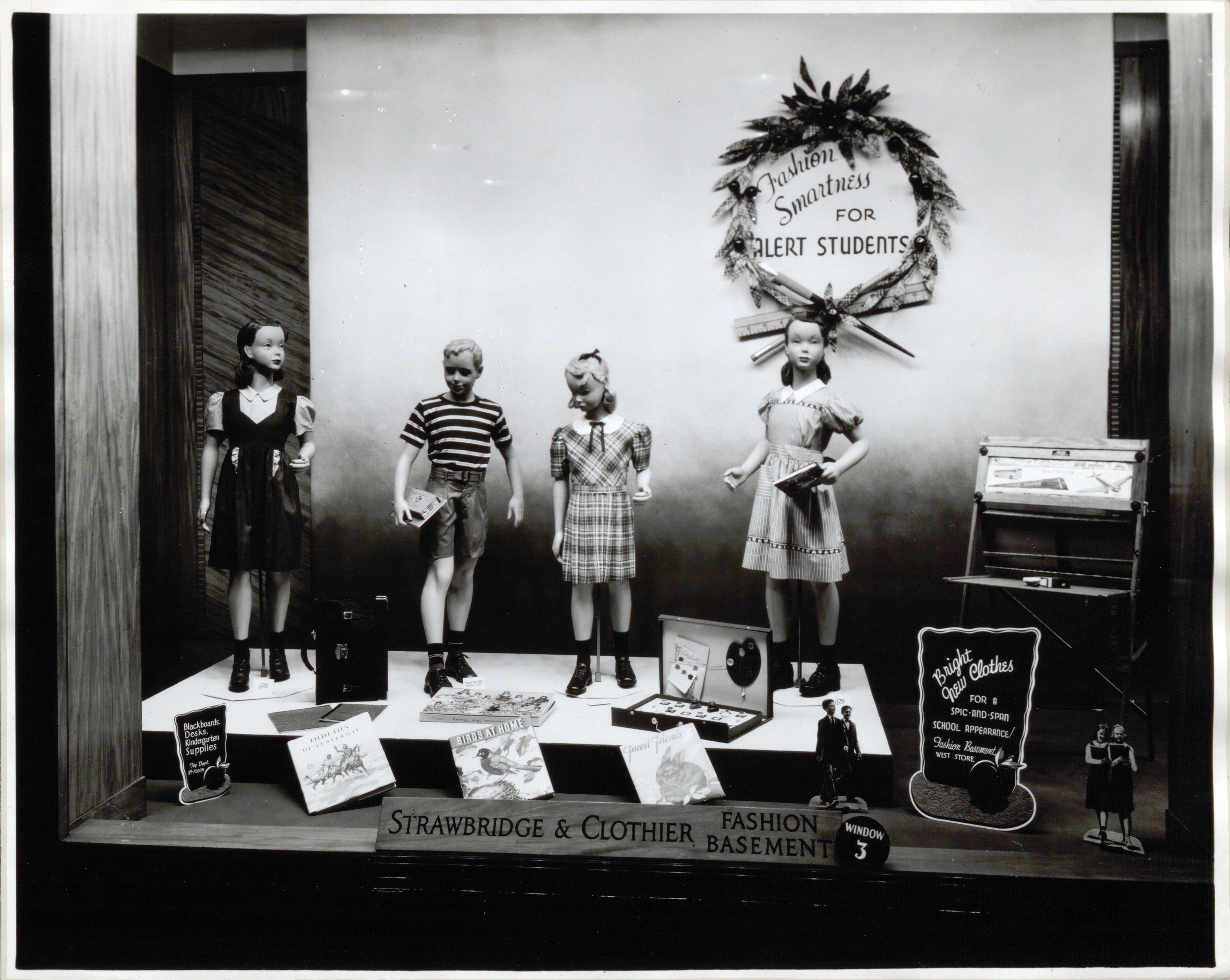 Photograph of a store window display for back to school supplies and clothing.