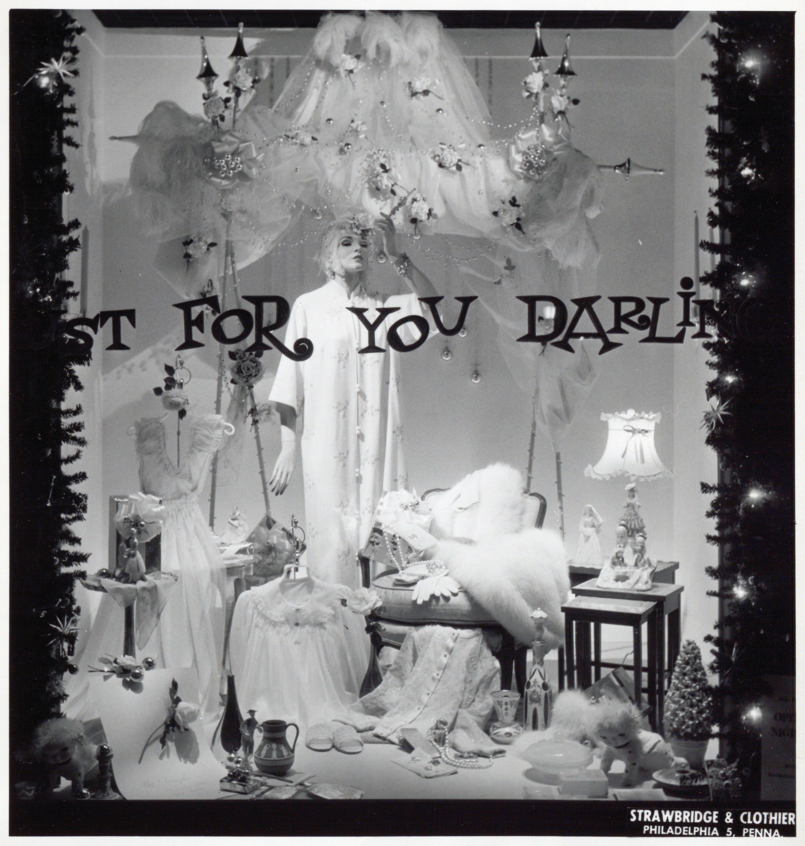 Black and white photograph of a Christmas themed store window display with the phrase 'Just for you darling' painted on the window.