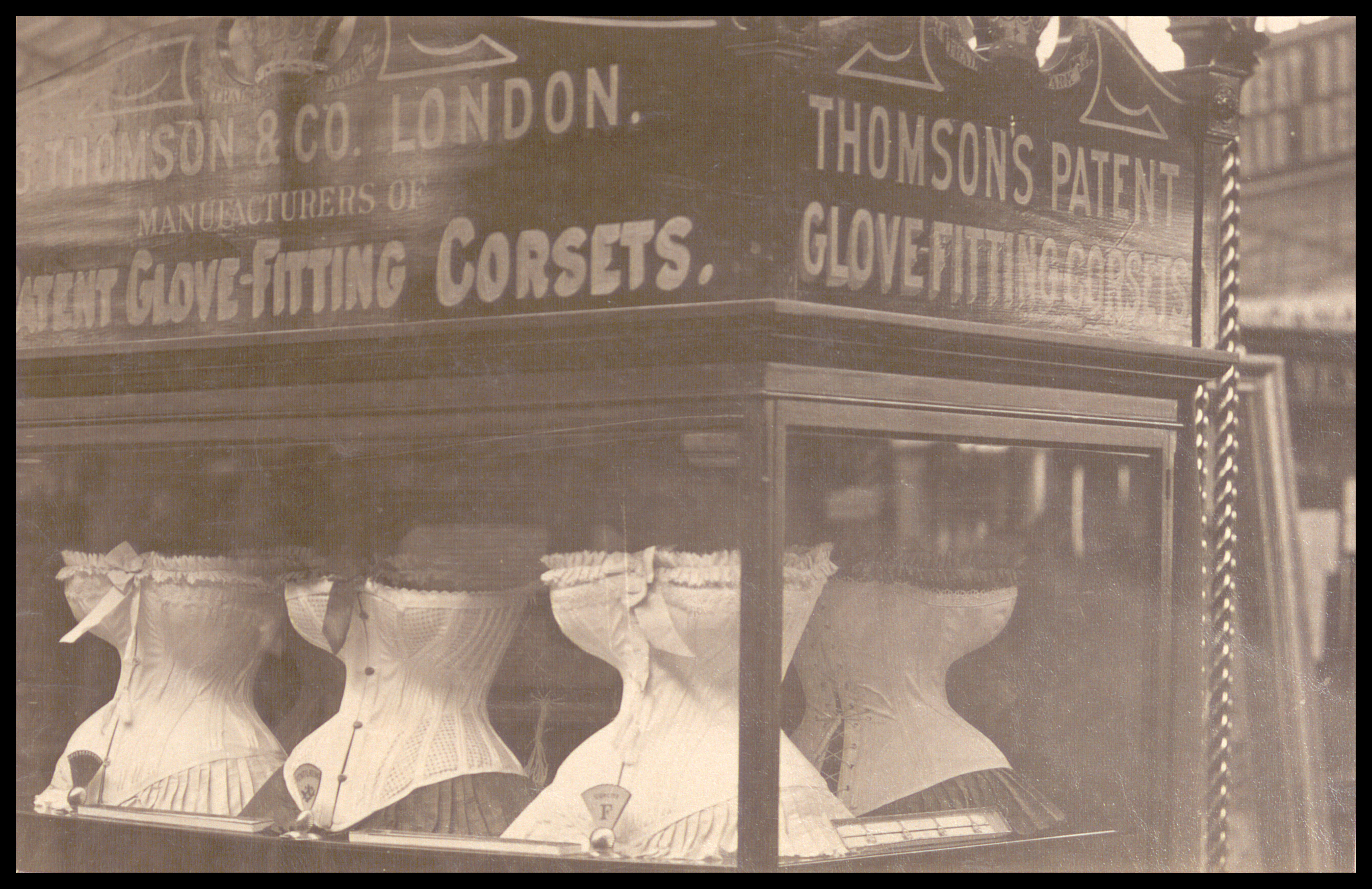 Black and white photograph of a display case featuring corsets