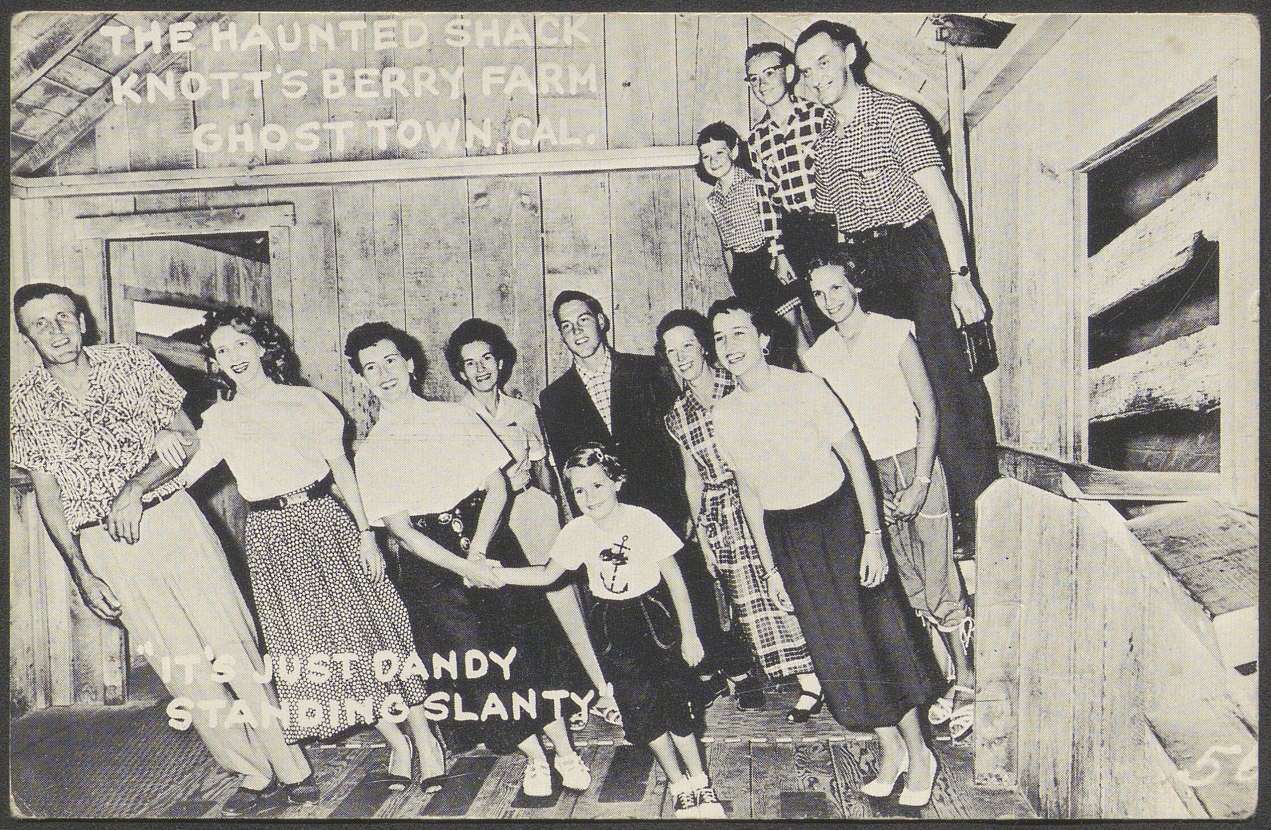 Postcard with black and white photograph of a group posed inside the Haunted Shack at Knott's Berry Farm 