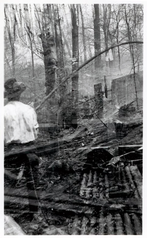 View of wreckage after a wheel mill explosion in Hagley Yard, with man standing in foreground.