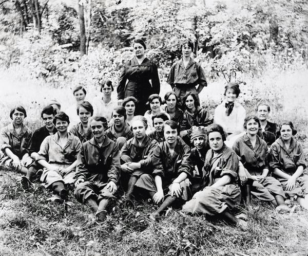 Black and white image of a large group of women in work clothes posing for a photograph on the grounds of the Brandywine Mills