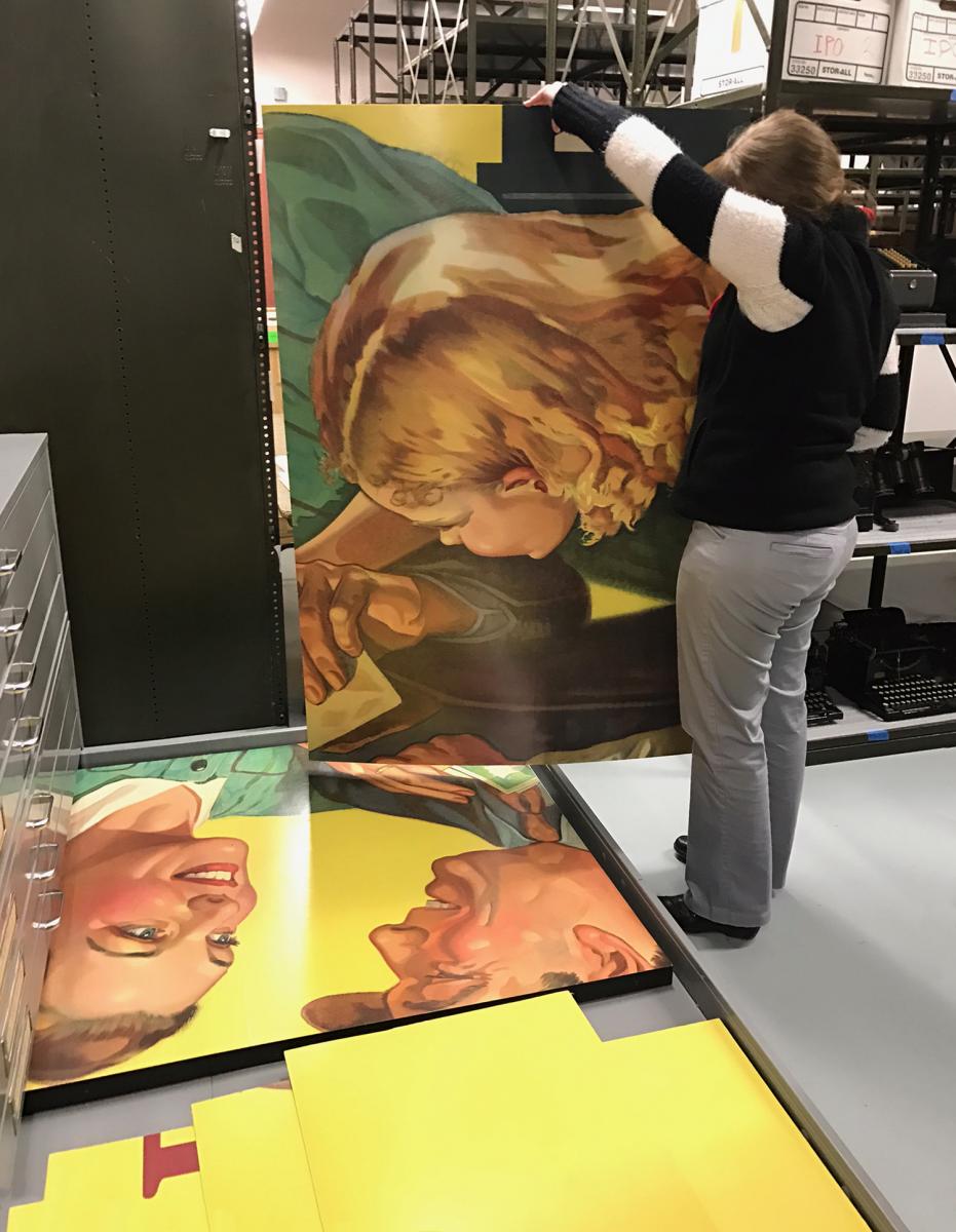 An archivist holds up a piece of the enormous billboard in the archives.