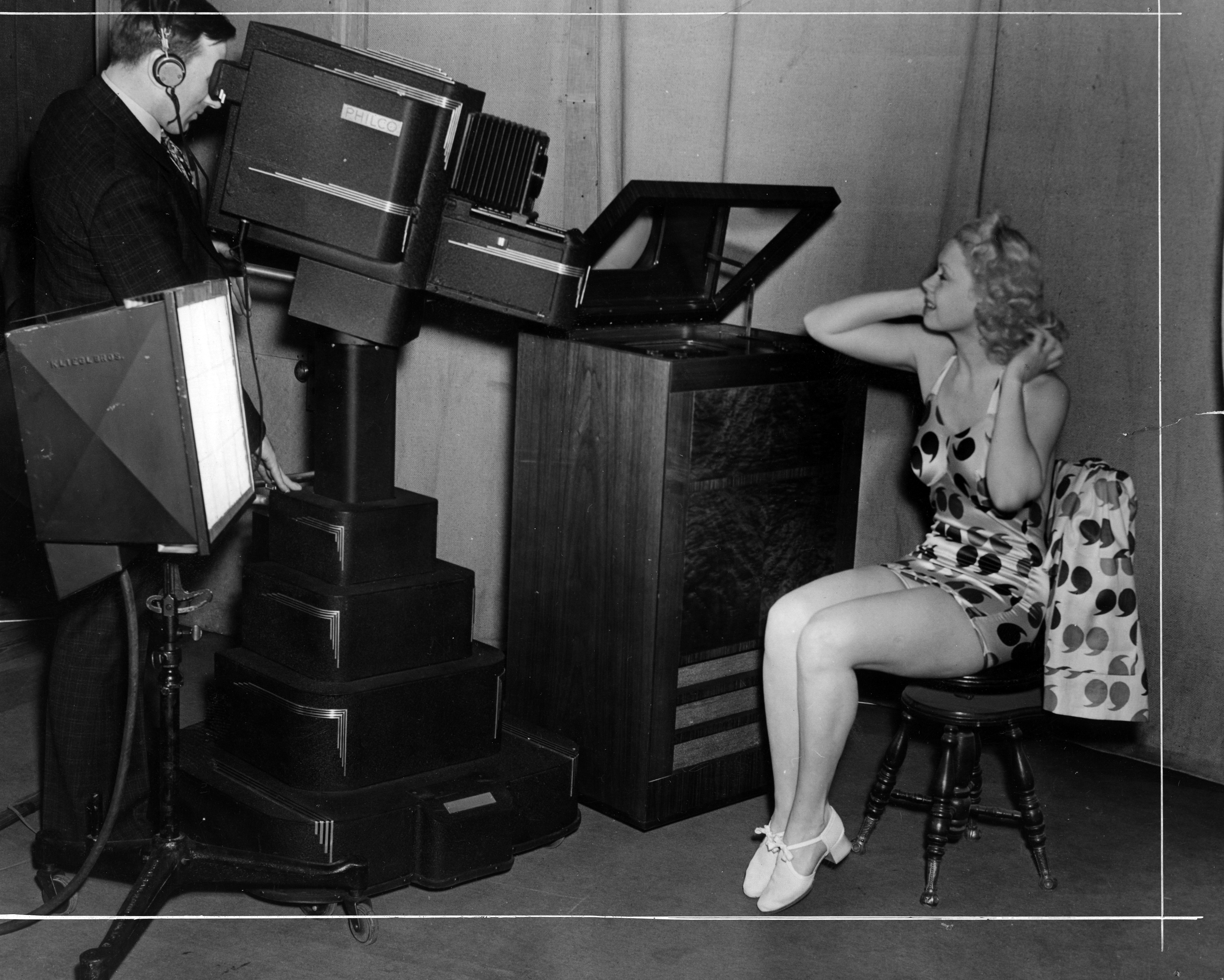 Toby Wing, screen and stage star, watches herself in the television receiving set as she performs before the new television equipment in the Philco Radio television station