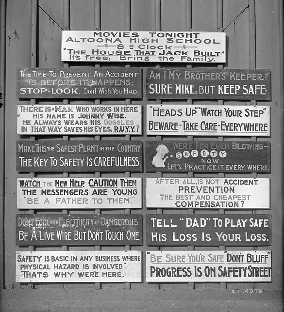Photograph showing a collection of wooden signs bearing slogans related to workplace safety.