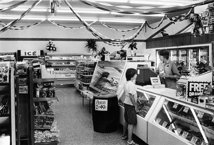 Inside of a wawa food market, a young boy pays at the register