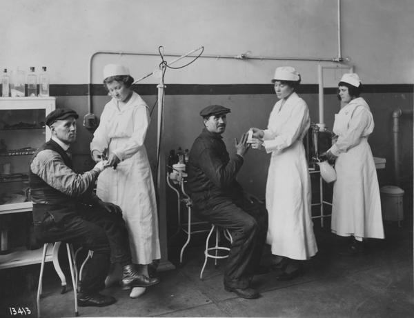 Black and white photograph of nurses and patients in machine shop dispensary.