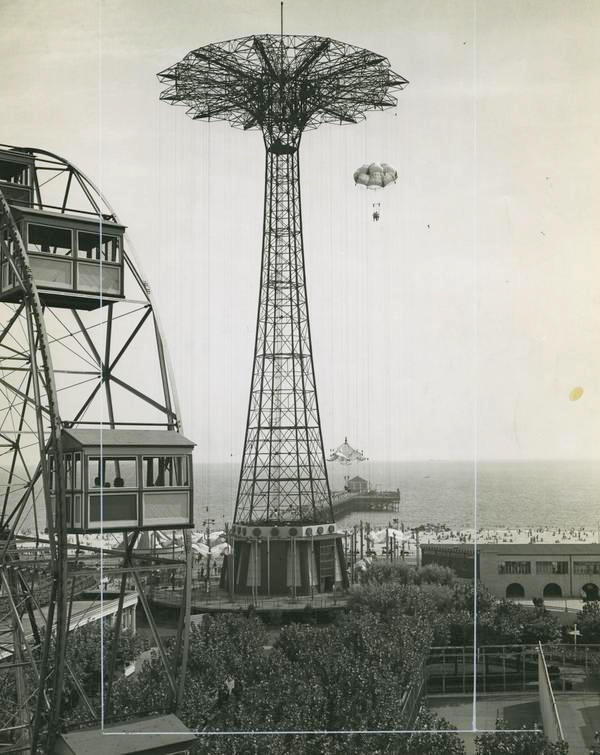 Black and white photograph, taken from a height, of a seaside amusement park. Main feature is the Parachute Jump ride.