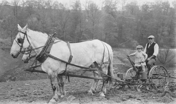 Black and white photograph of Howard Seal and his granddaughter, Eleanor Seal, planting corn with horse-drawn planter.
