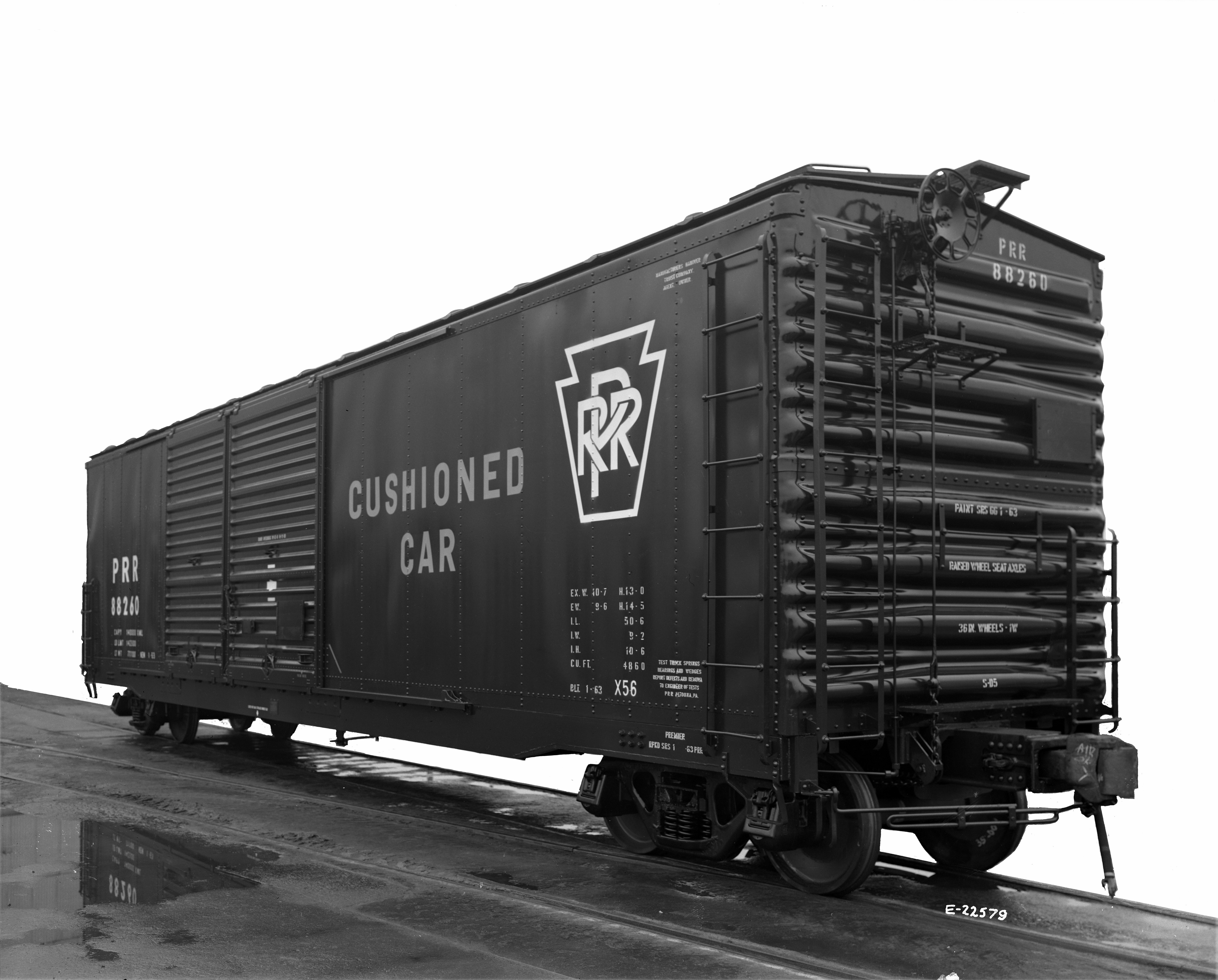 Black and white, 3/4 view of a railroad box car. Stenciling on side reads "Cushioned car".