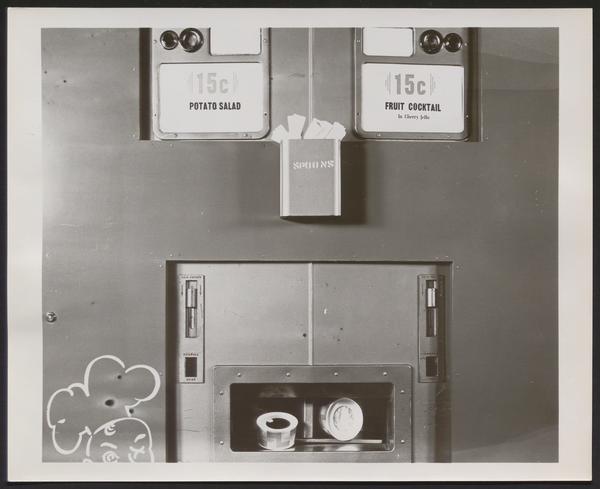 Close up black and white photograph of a food vending machine offering potato salad and fruit cocktail in cherry jello.