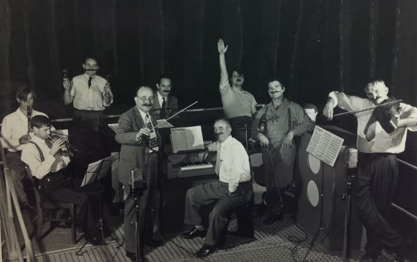 Men wear large false mustaches and play musical instruments